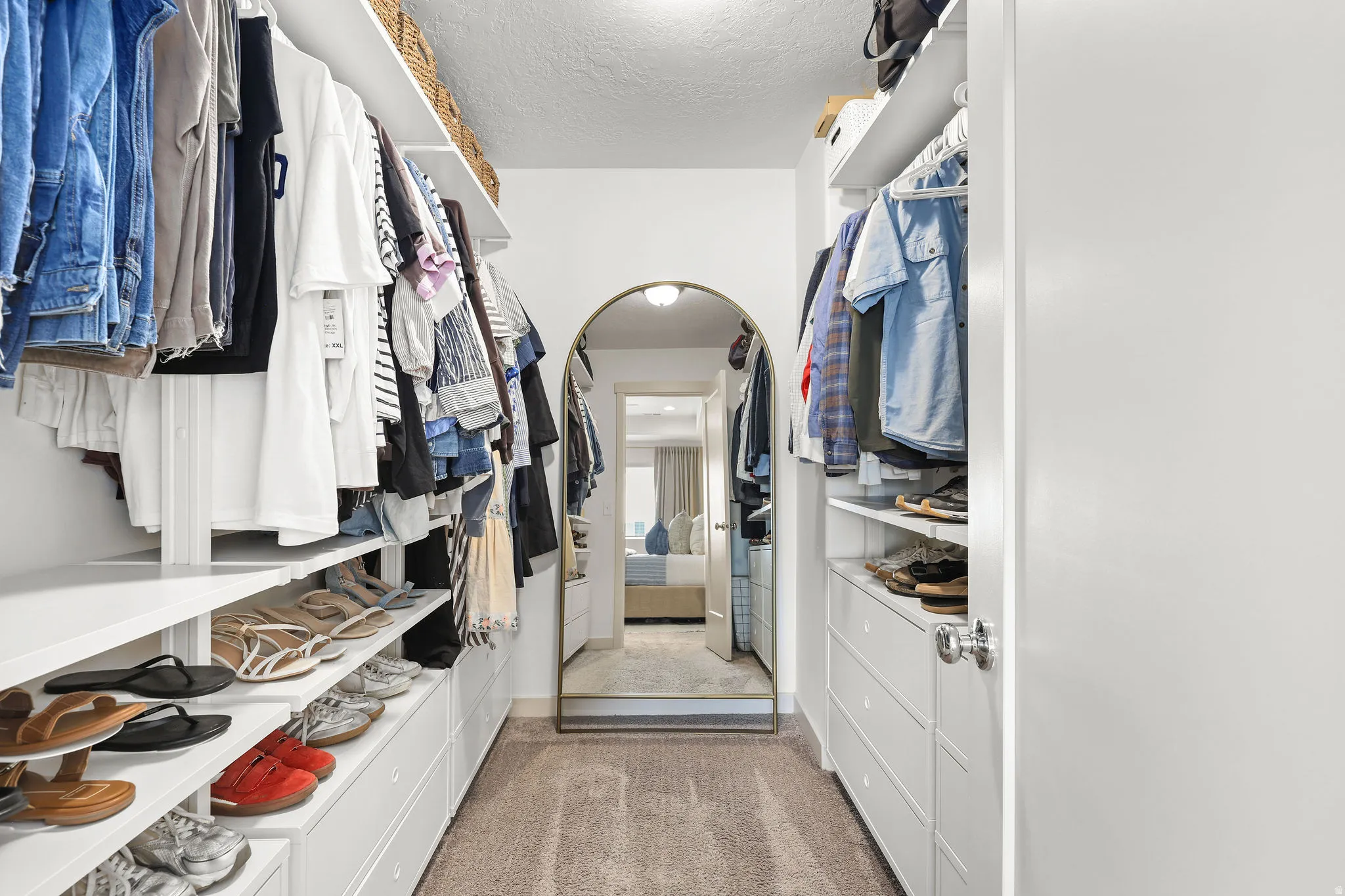 Walk-through closet featuring built-in shelving, hanging rods, integrated drawers, and carpet flooring