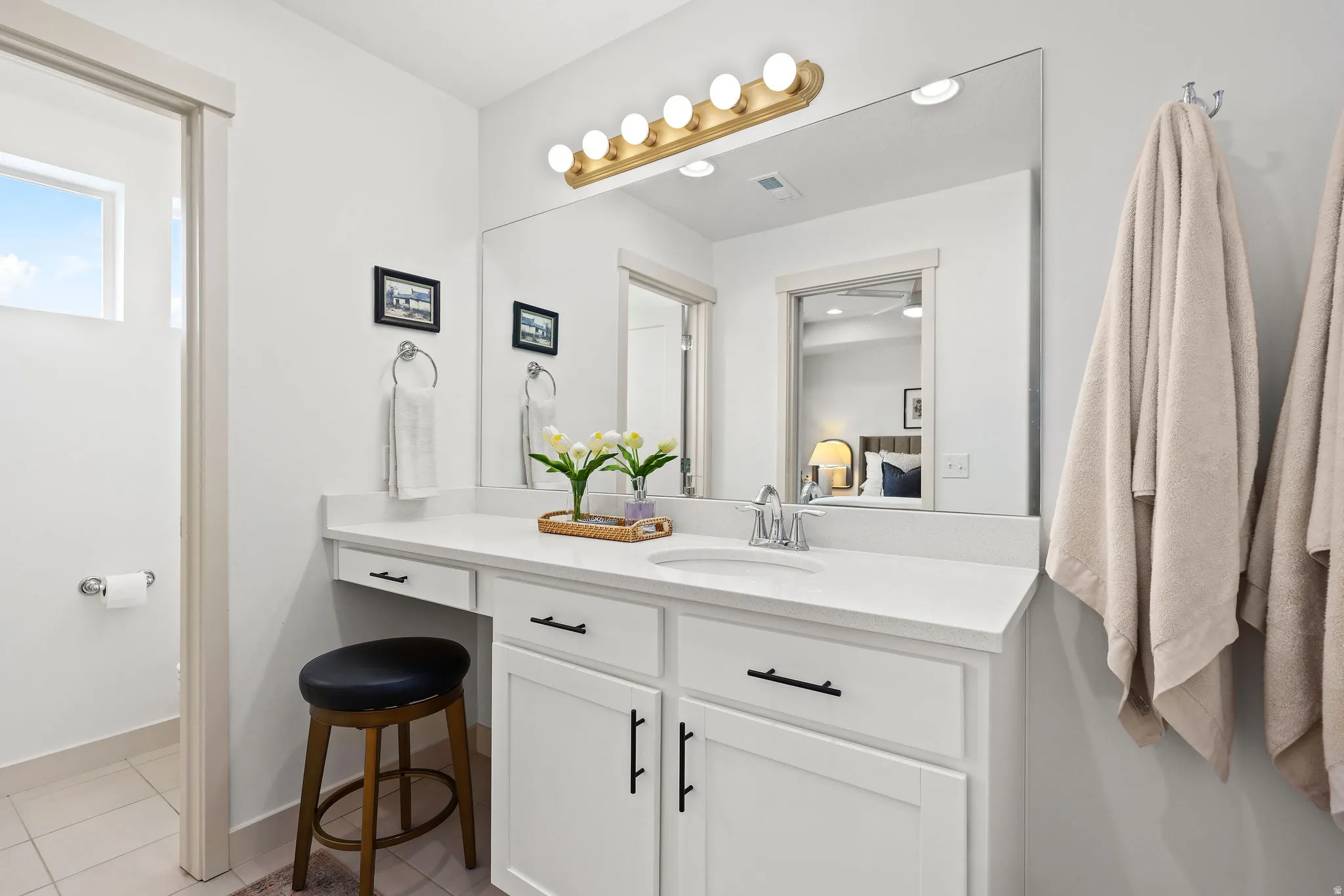 Bathroom vanity featuring a single basin sink, white cabinetry with black hardware, and a light-colored countertop