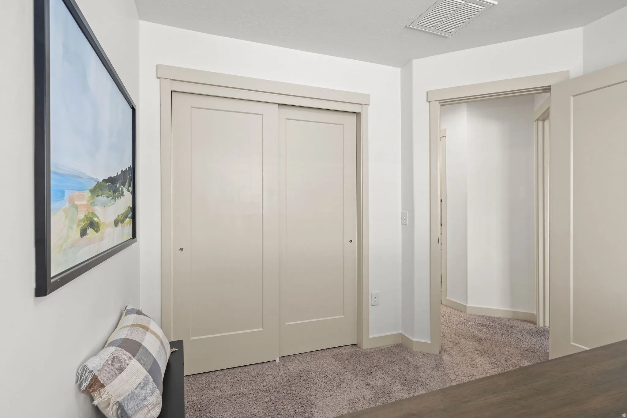 Bedroom featuring a sliding closet door, neutral wall color, and plush carpet flooring