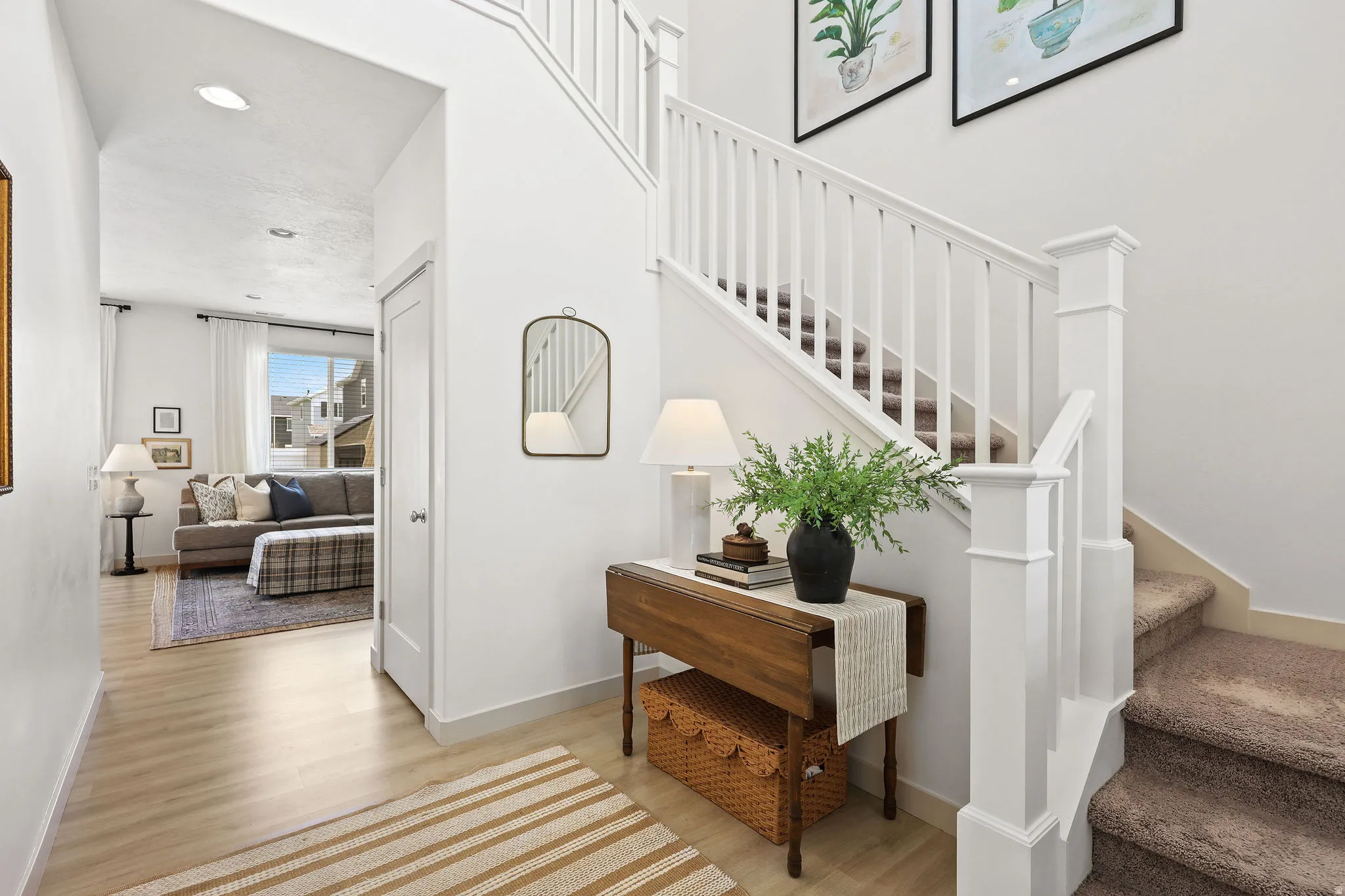 Entry foyer featuring light wood-finish flooring, white walls, and a staircase with white balusters and carpeted treads