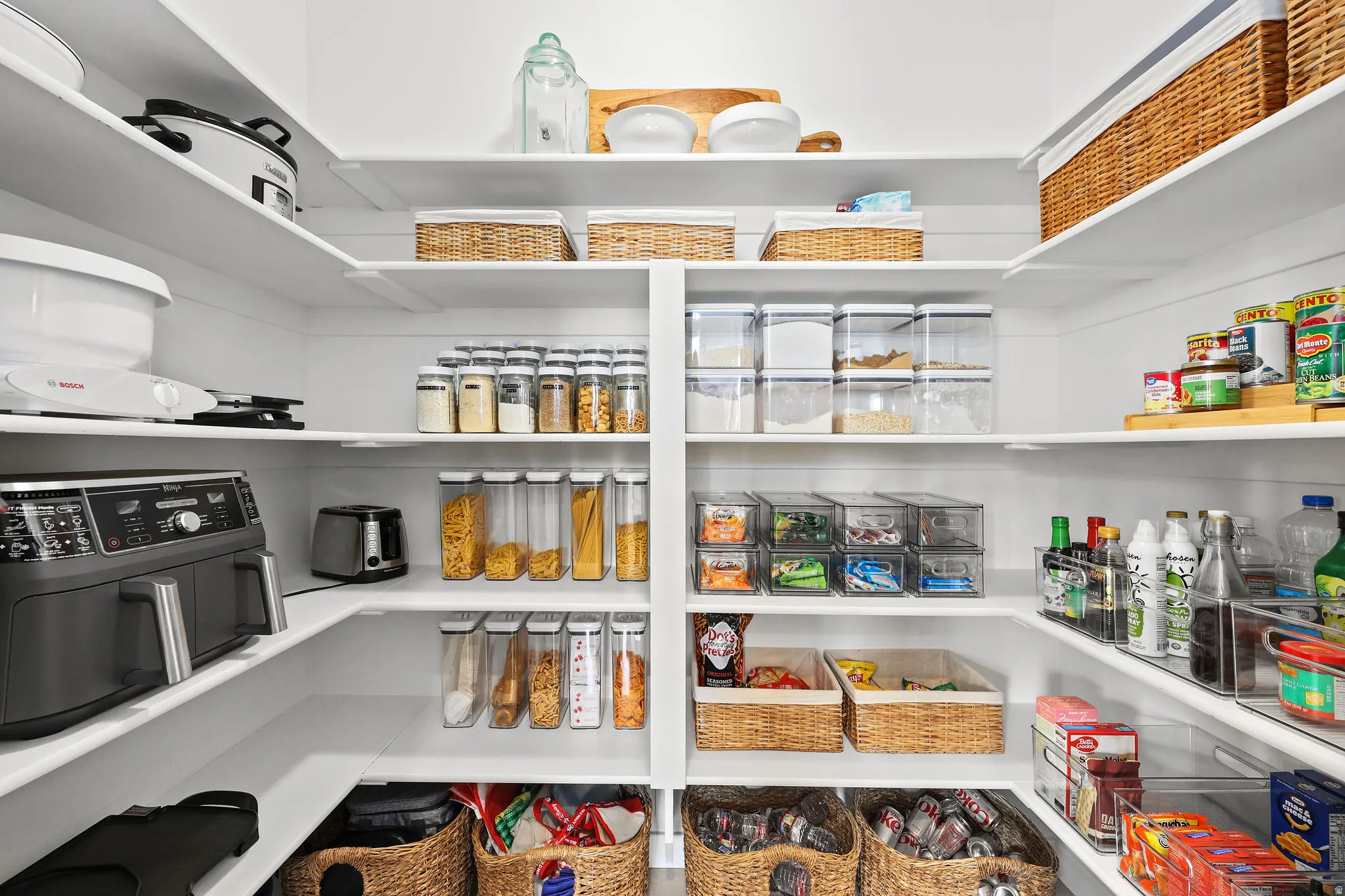 Custom pantry featuring white shelving, ample storage solutions, and built-in corner shelving
