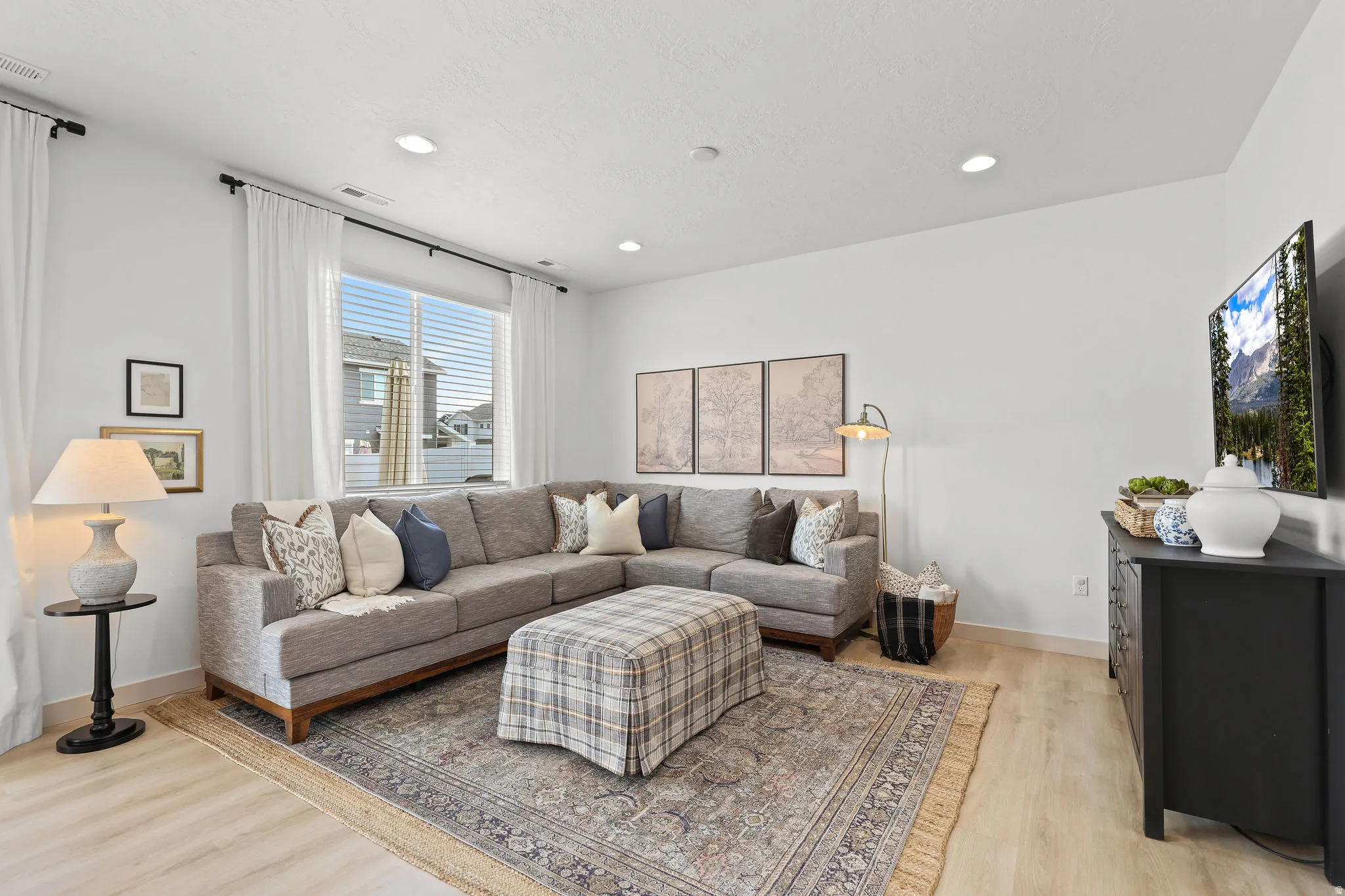 Bright living area featuring light wood-finish flooring and recessed lighting