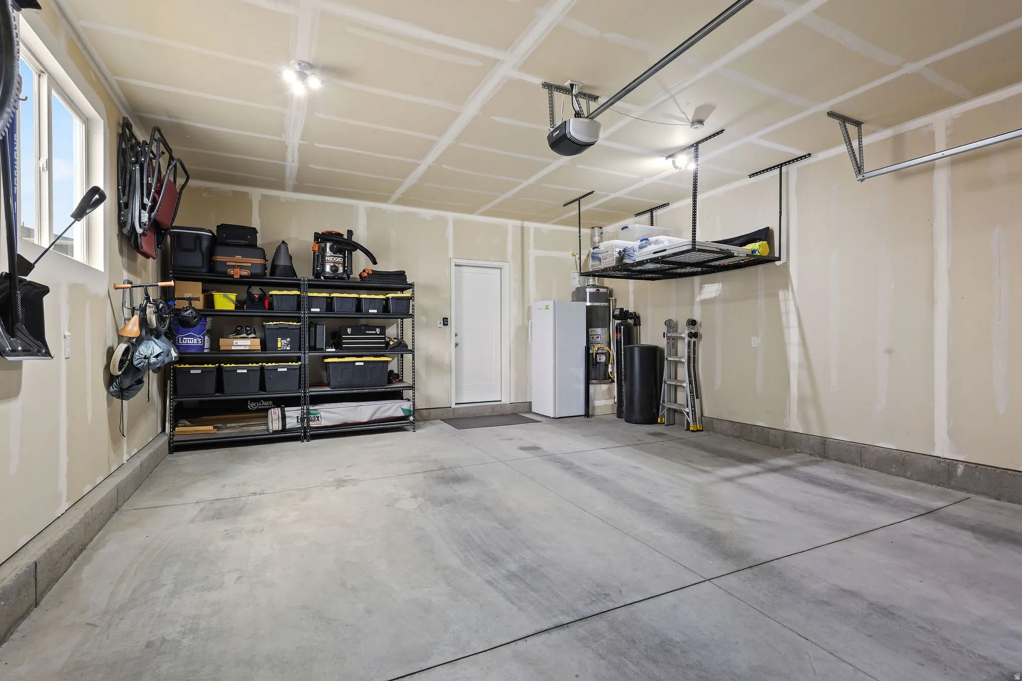 Spacious garage featuring concrete flooring, overhead lighting, and two windows