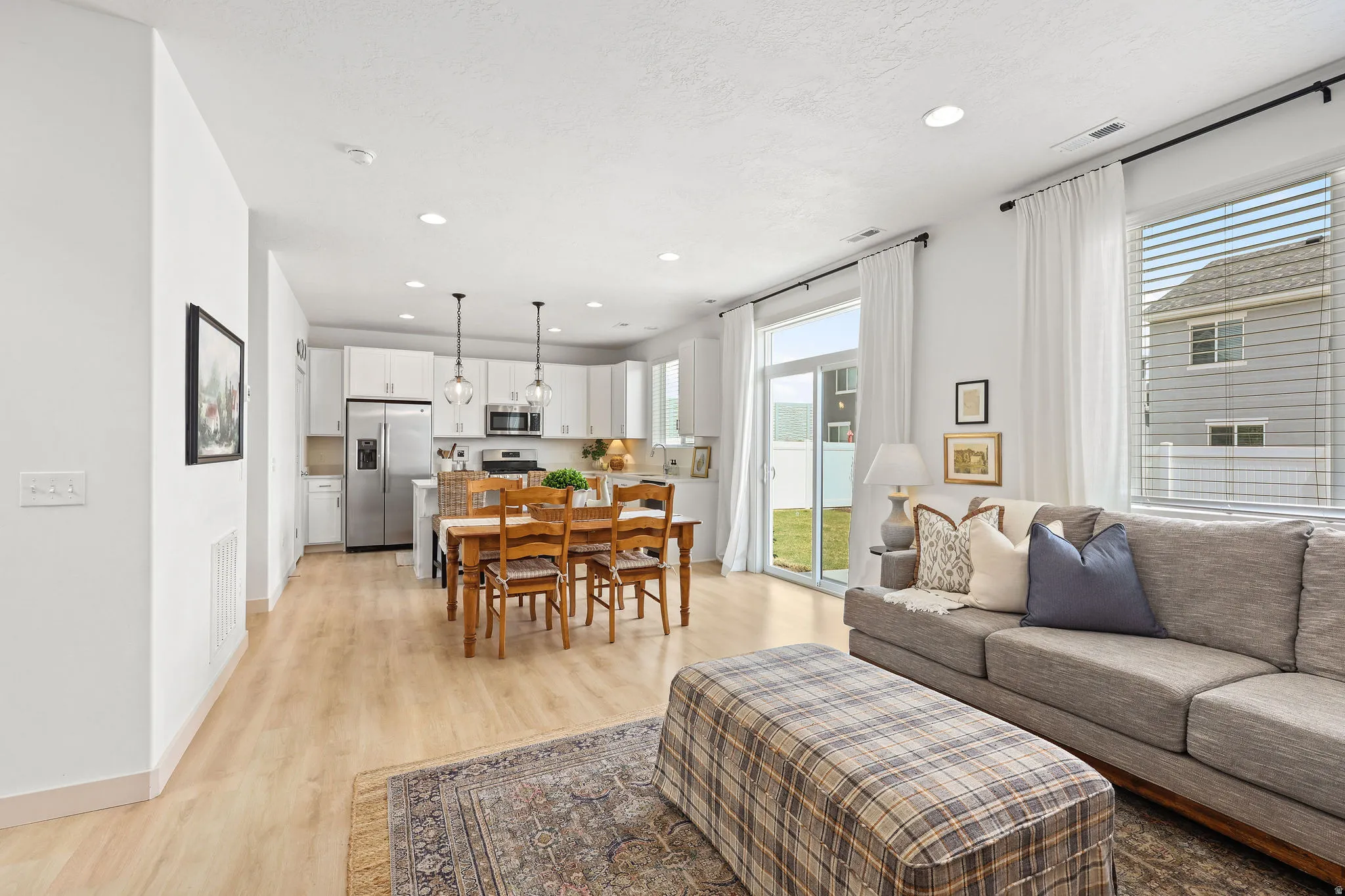 Open-concept living space featuring wood-finish flooring, recessed lighting, and a sliding glass door leading to the backyard