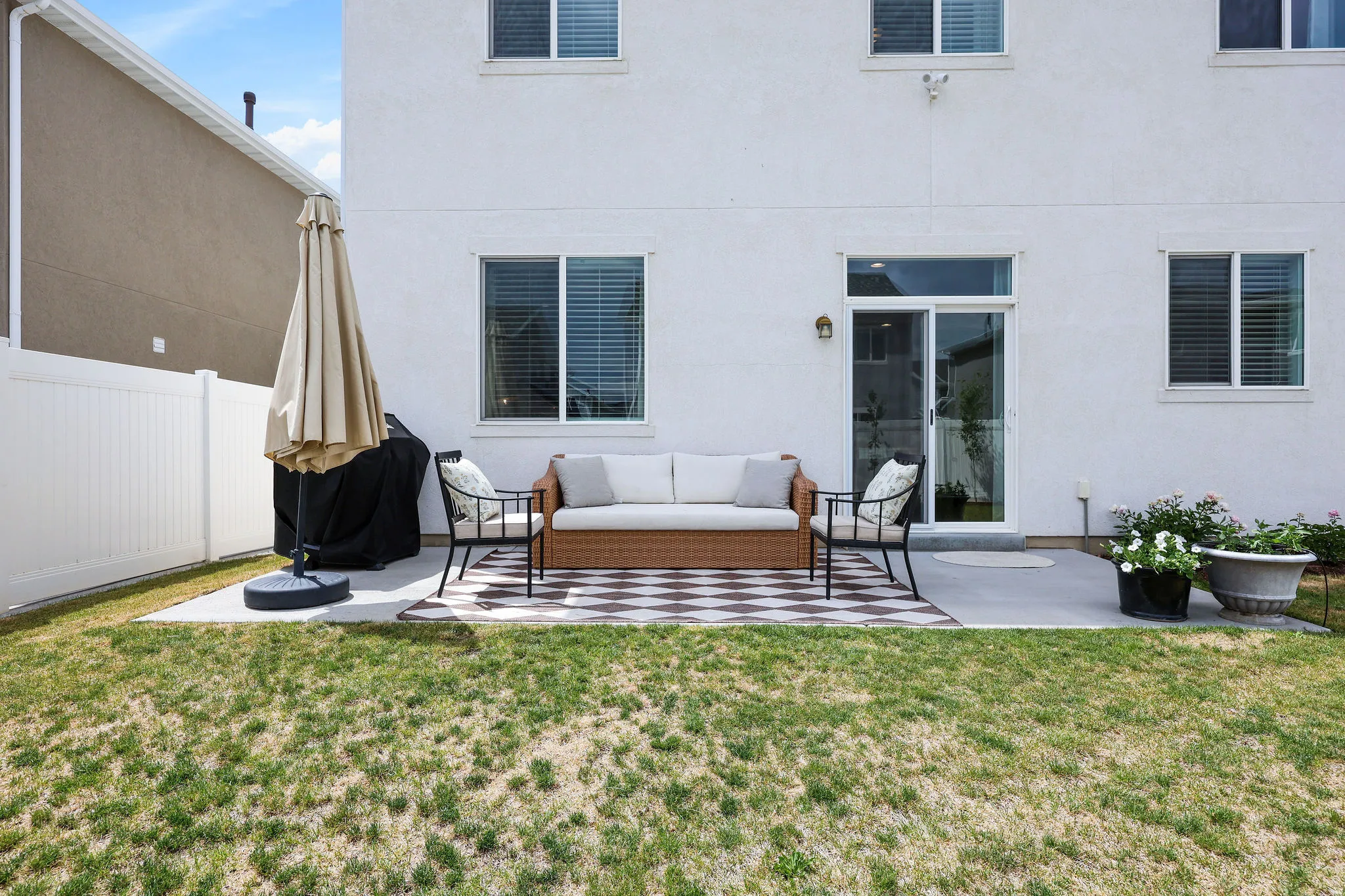 Rear exterior featuring a concrete patio, sliding glass door, and white vinyl fencing