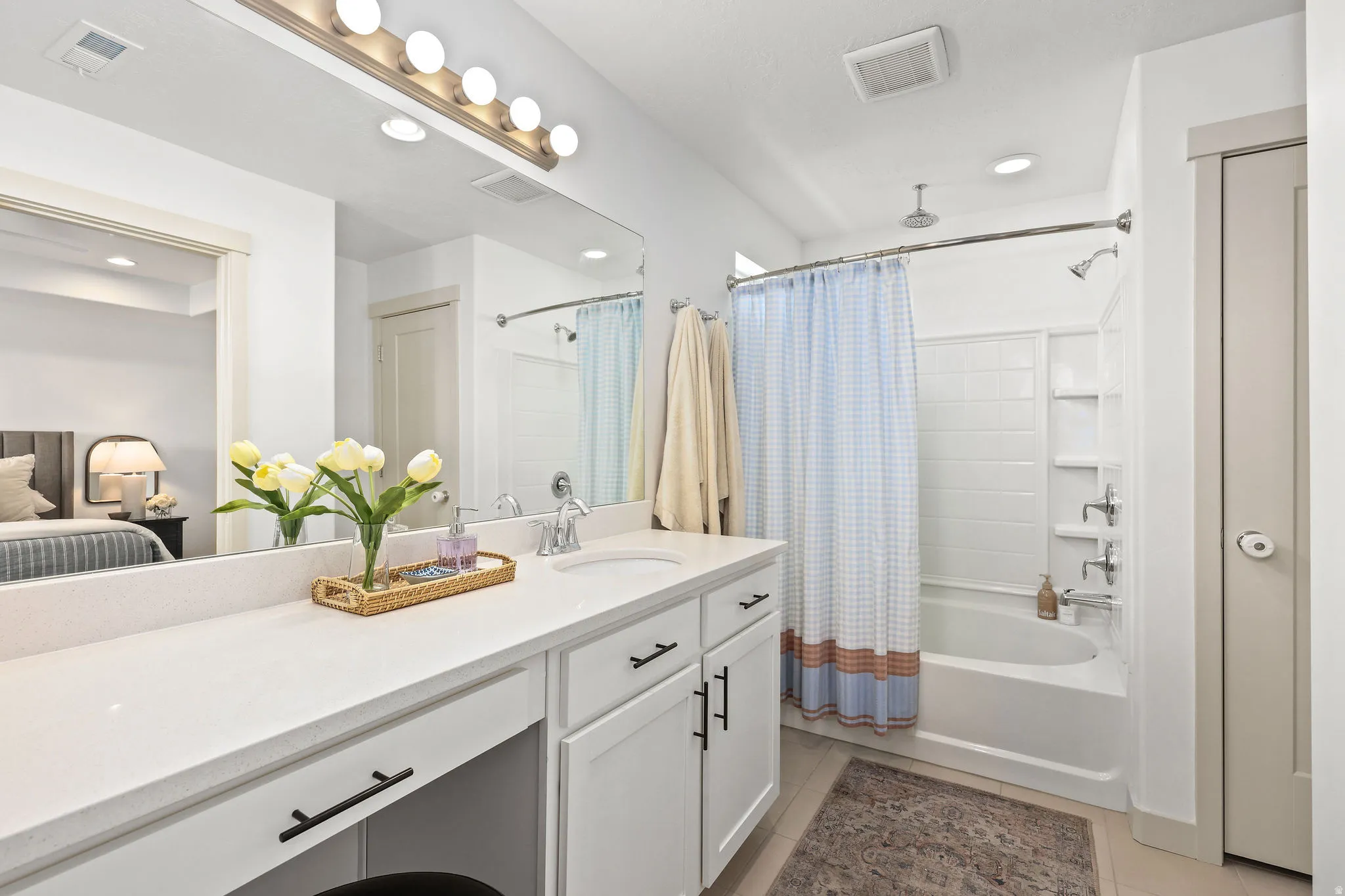 Bathroom featuring a double vanity with stone countertops, integrated sink, brushed nickel fixtures, and white cabinetry with matte black hardware