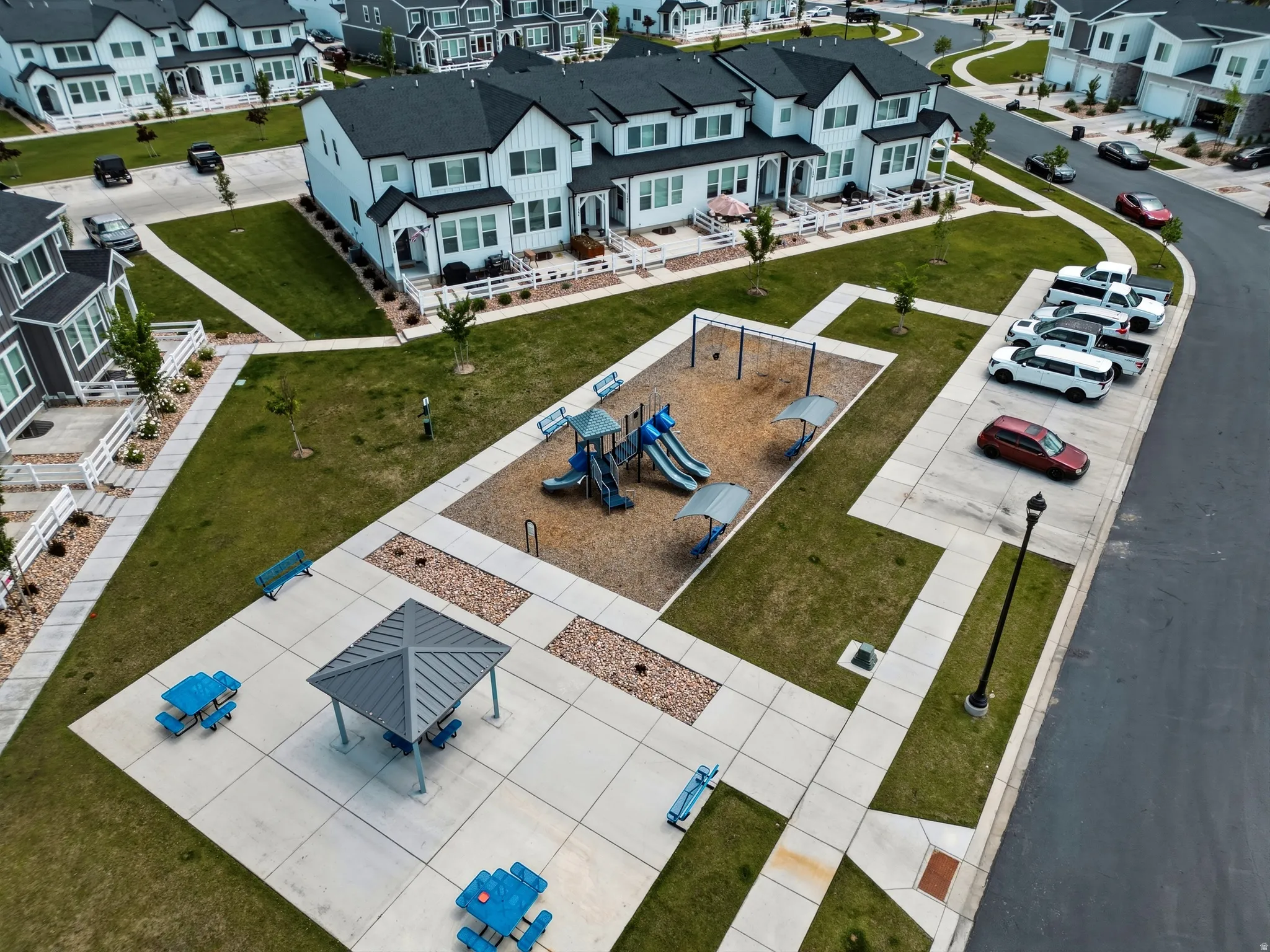 Community greenspace featuring a playground with swings and slides, a covered picnic area, and additional seating