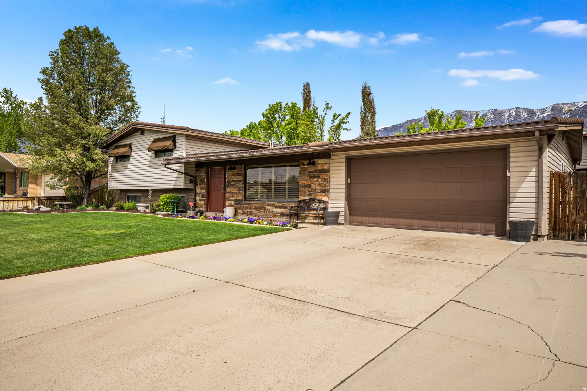 Split-level residence featuring a stone facade, beige siding, and a two-car garage