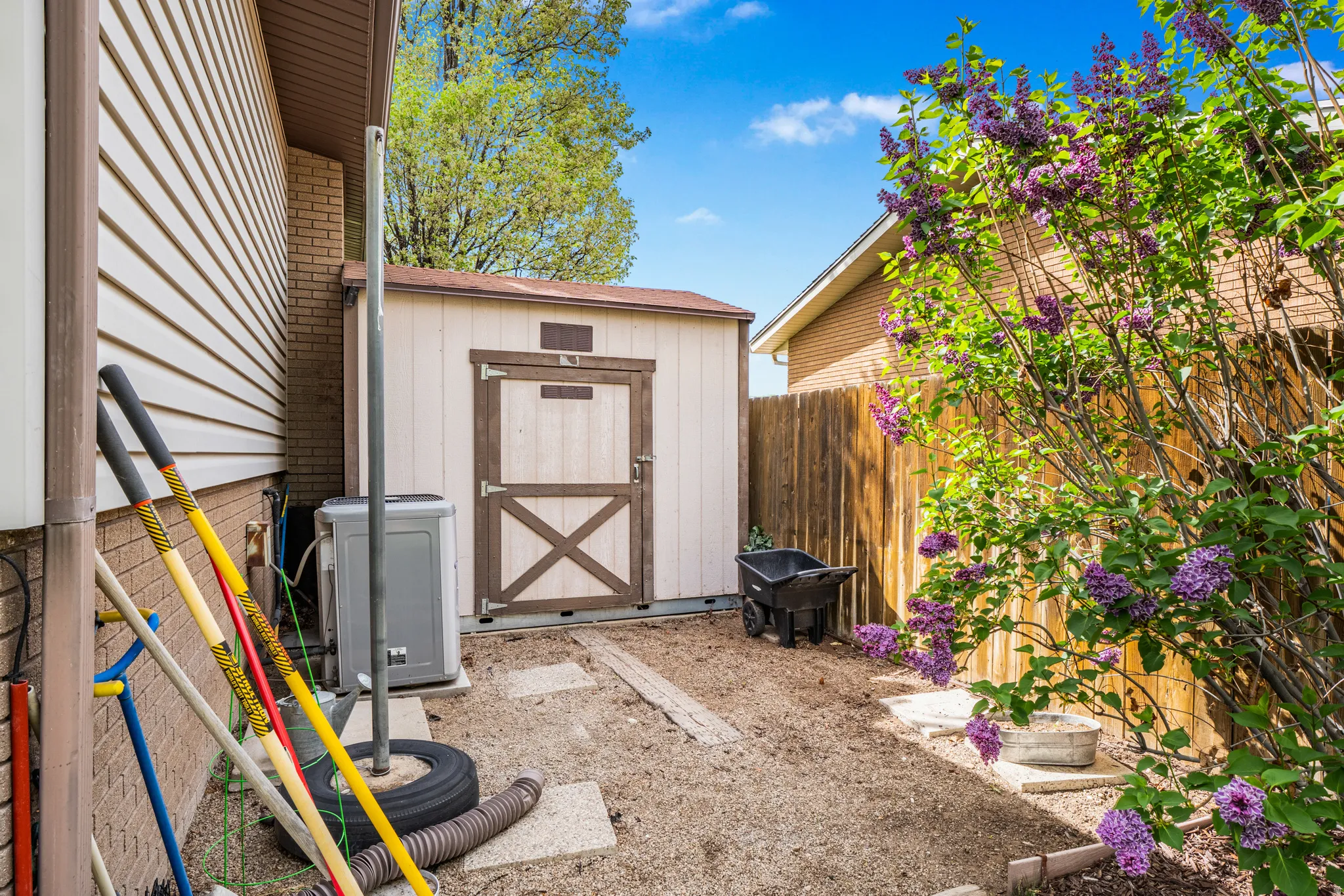 Side yard featuring a storage shed with barn-style doors, a privacy fence, and mature blooming shrubs