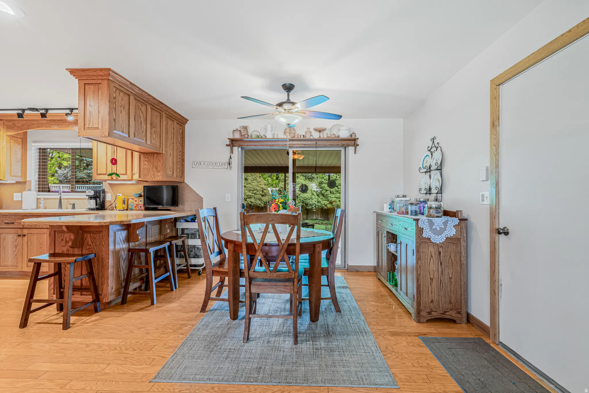 Open-concept dining area with wood-finish flooring, a ceiling fan, and sliding glass door access to the exterior