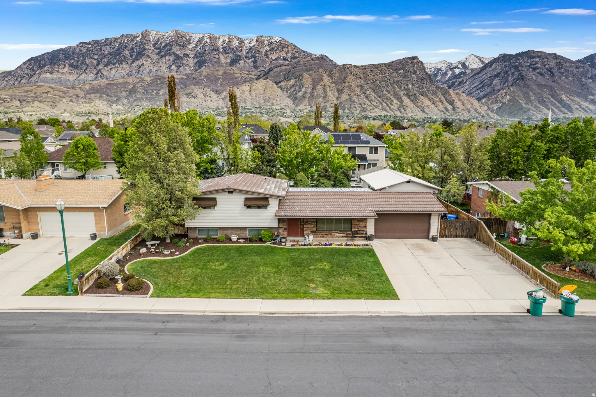 Ranch-style residence featuring a manicured front lawn and mature landscaping