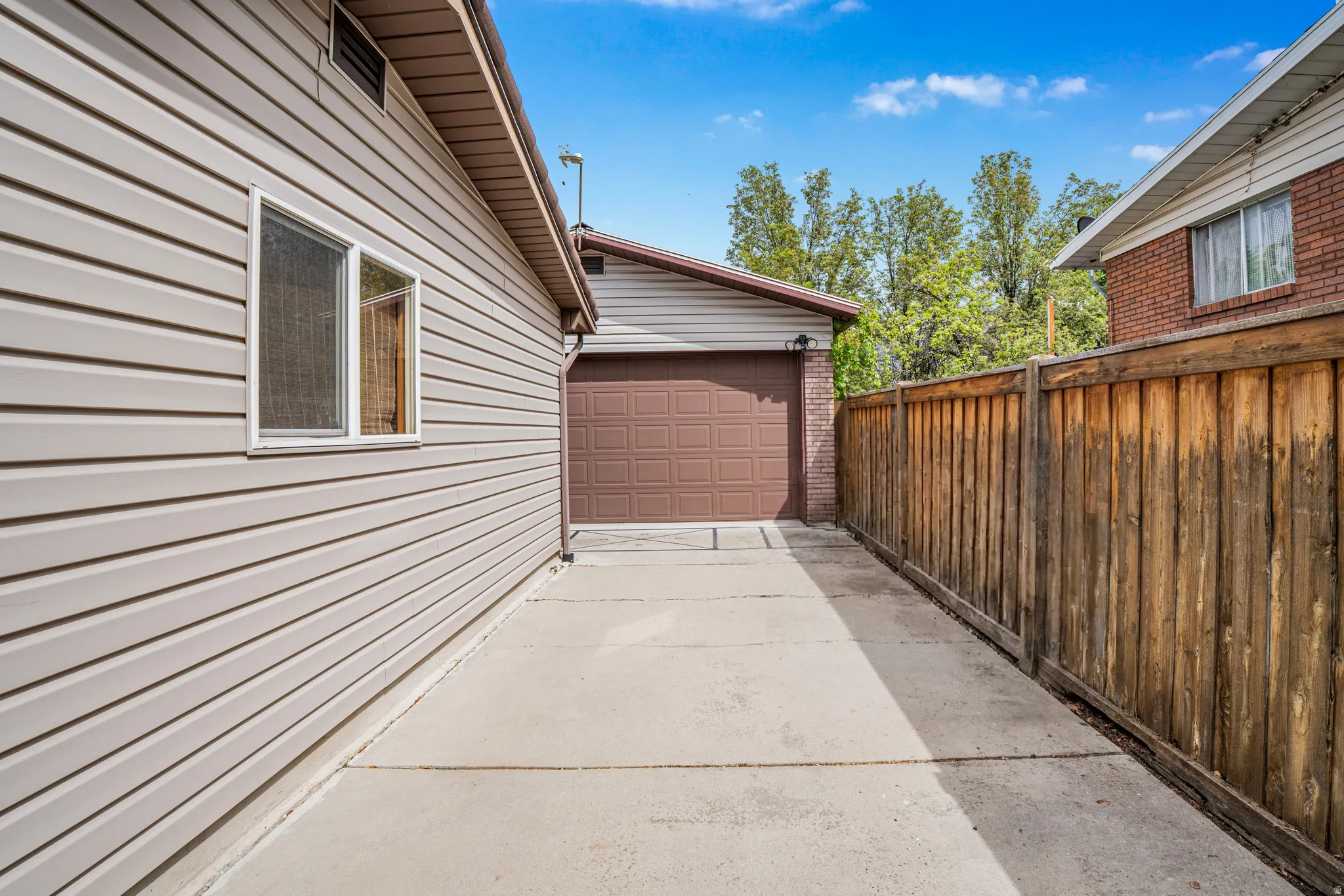 Concrete driveway extending to a detached garage with a brown panel door
