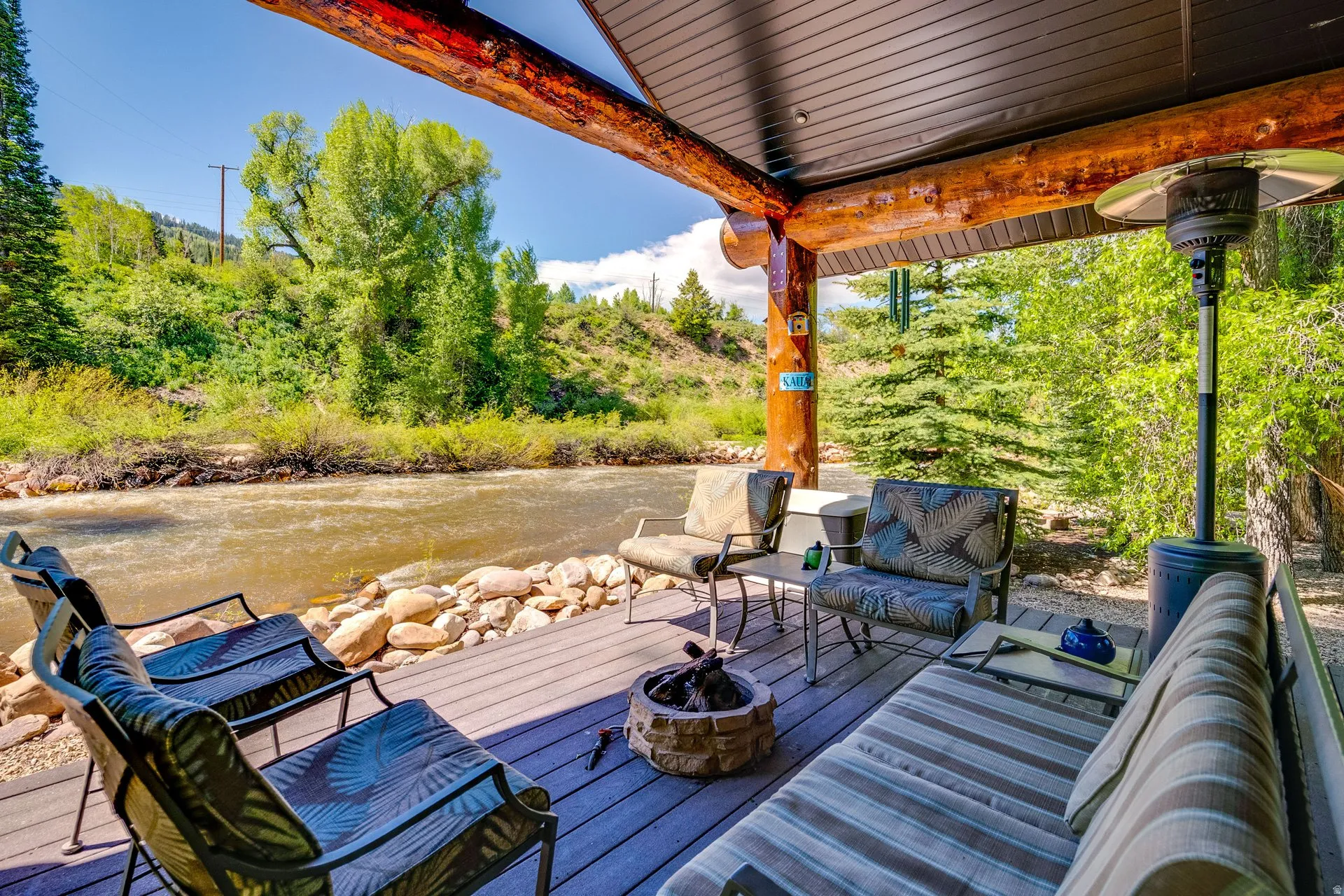 Covered outdoor deck with exposed log beams overlooking a river