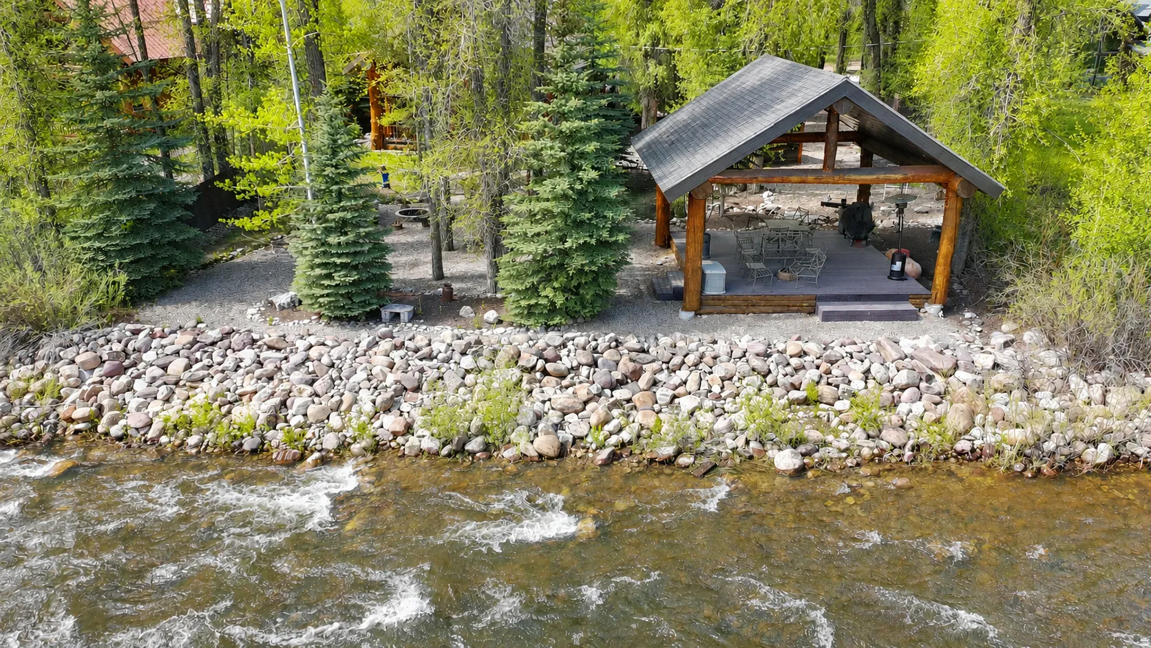Waterside gazebo featuring a gabled roof, exposed wood beams, and a composite deck