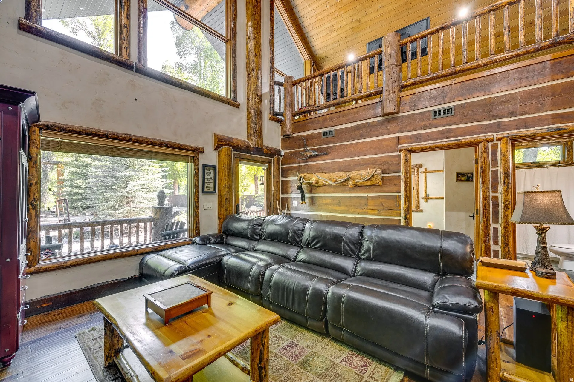 Vaulted ceiling great room featuring prominent wood beams and an upper-level balcony