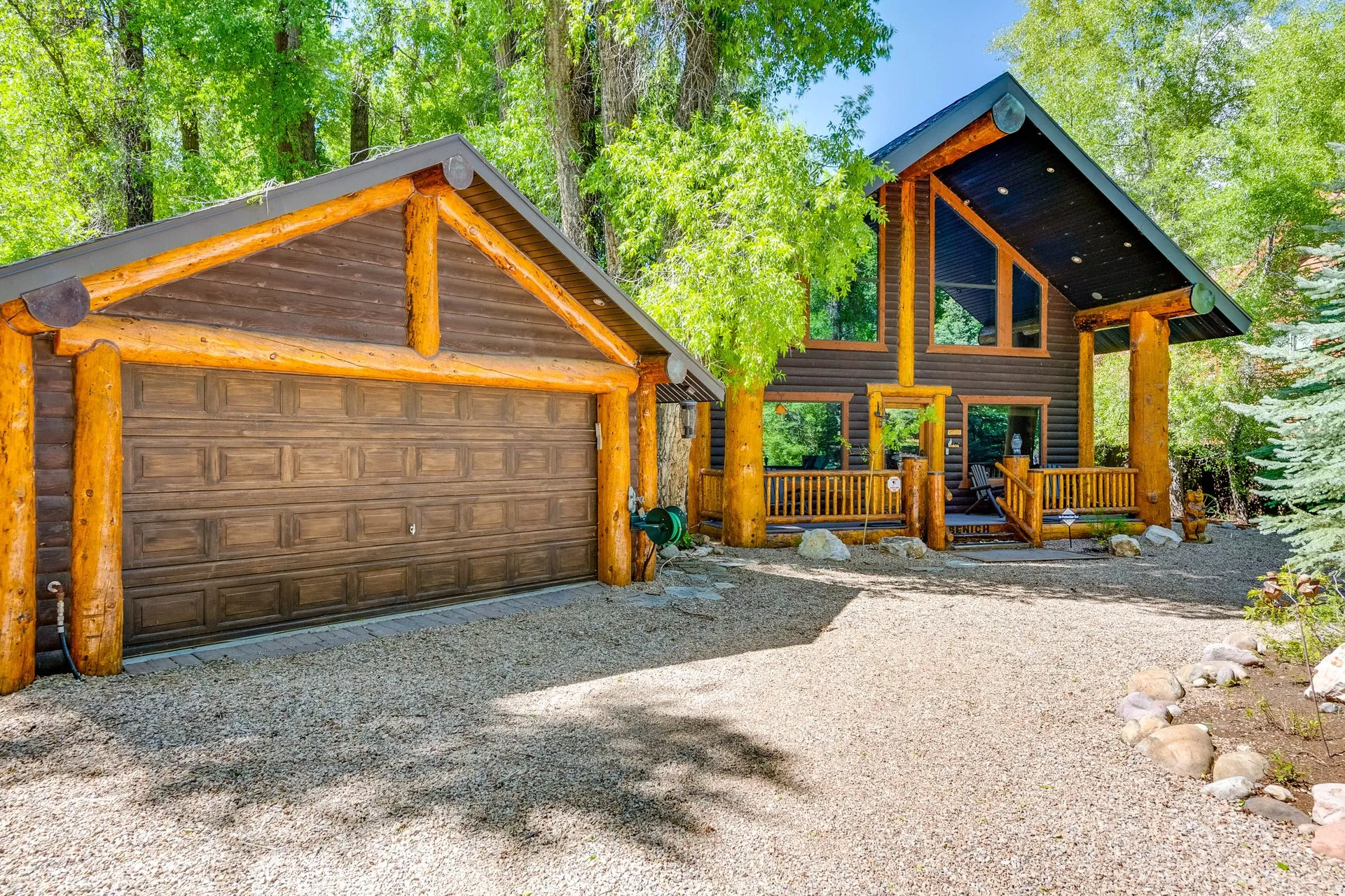 Log-sided residence featuring a prominent gravel driveway and an attached two-car garage