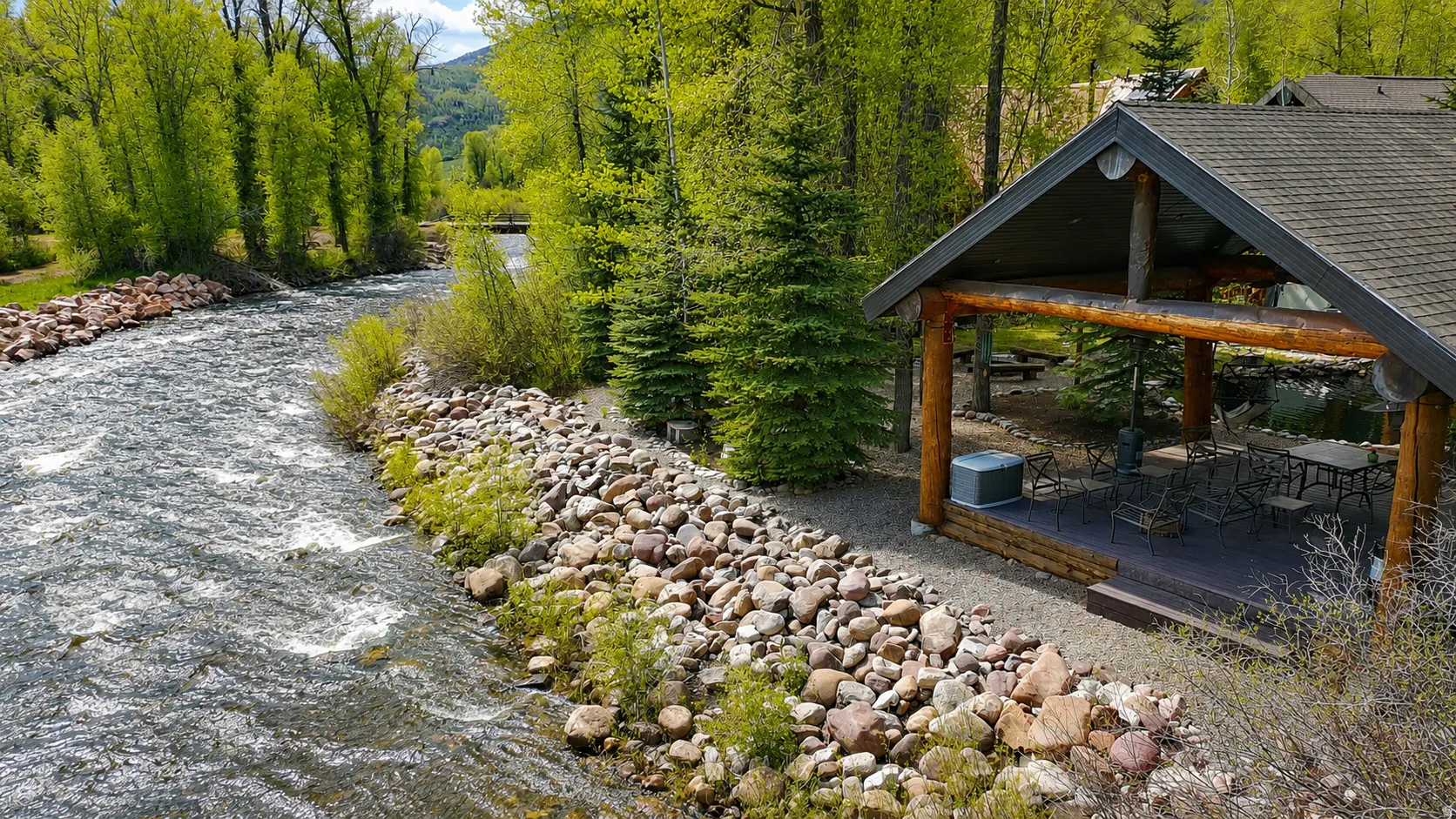 Riverfront outdoor pavilion featuring a gabled roof and exposed log beams