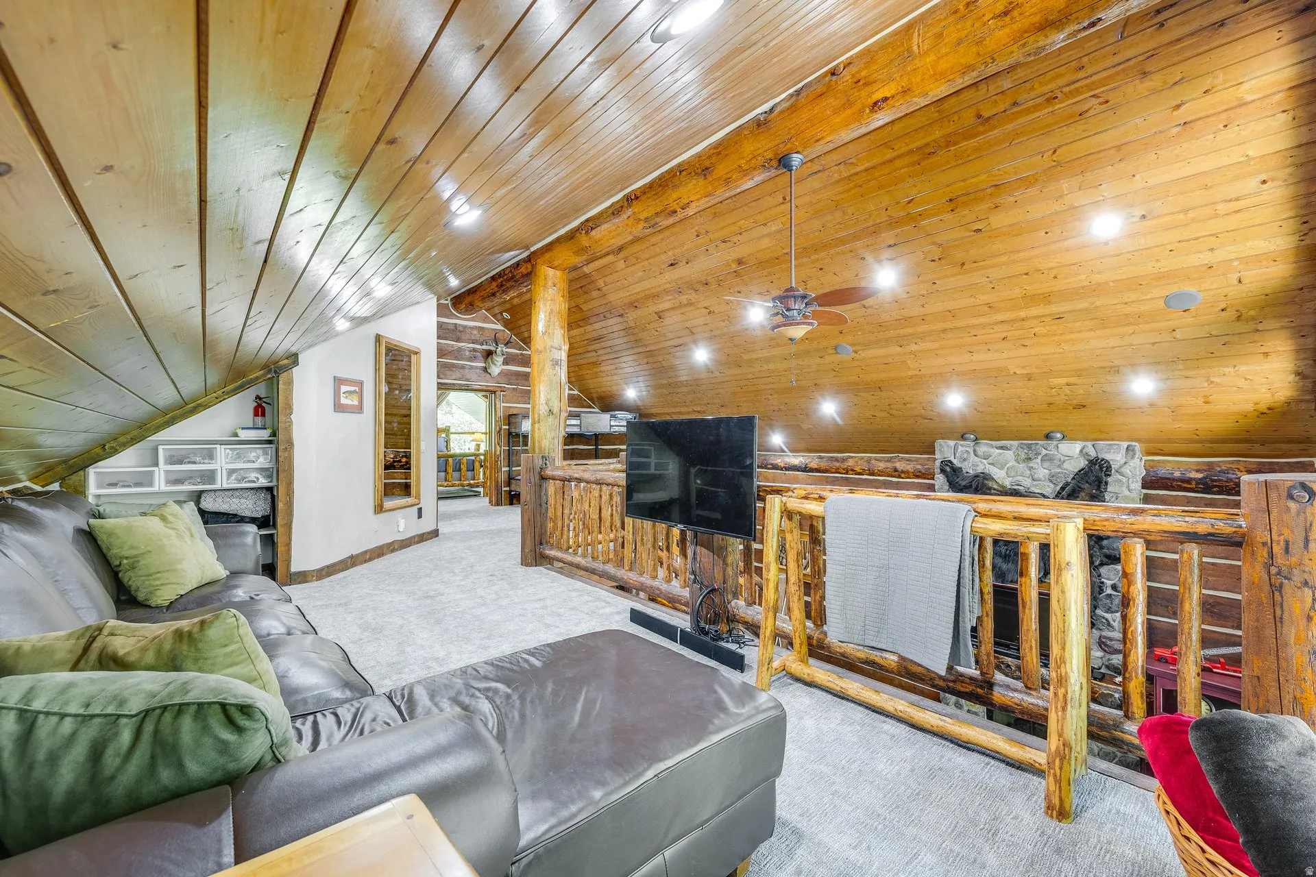 Expansive loft space featuring wood-paneled sloped ceilings, exposed wood beams, and recessed lighting