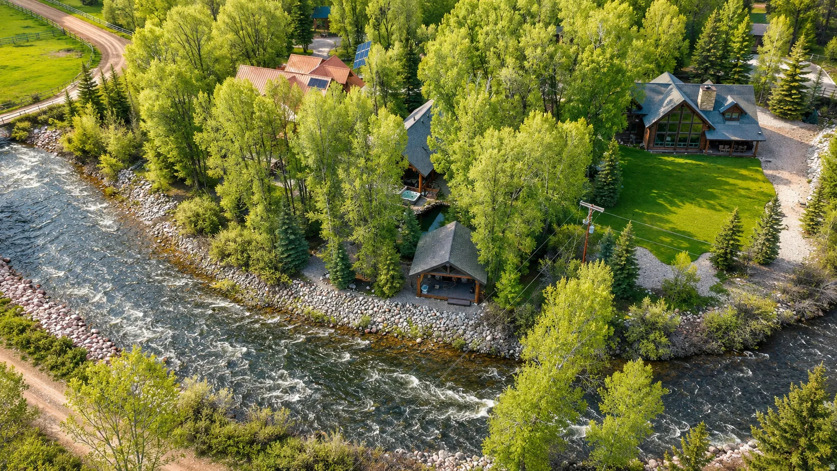 Riverside property featuring a main residence, a guest residence, and a covered pavilion structure