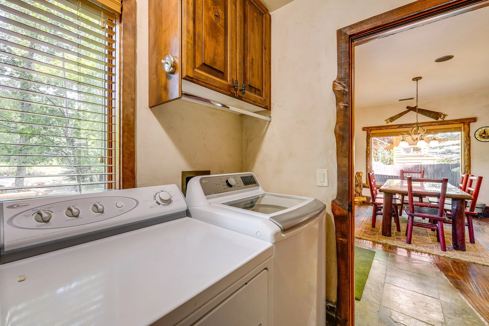 Dedicated laundry area featuring wood-finish cabinetry and a window with wood blinds