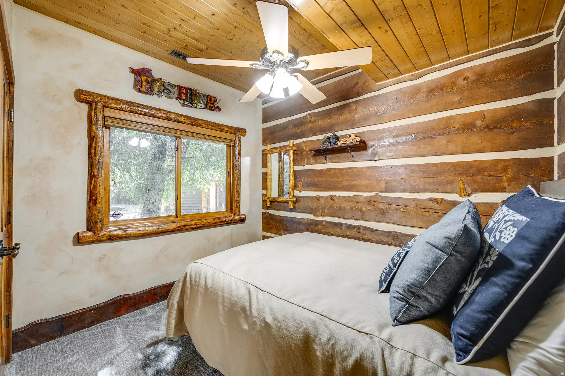 Rustic bedroom featuring log wall construction and a natural wood plank ceiling