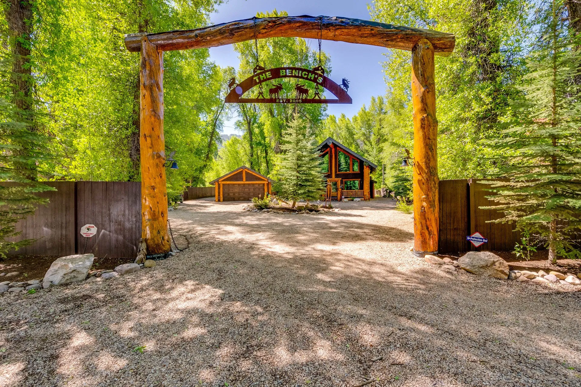 Gravel driveway leading to a custom log archway entrance