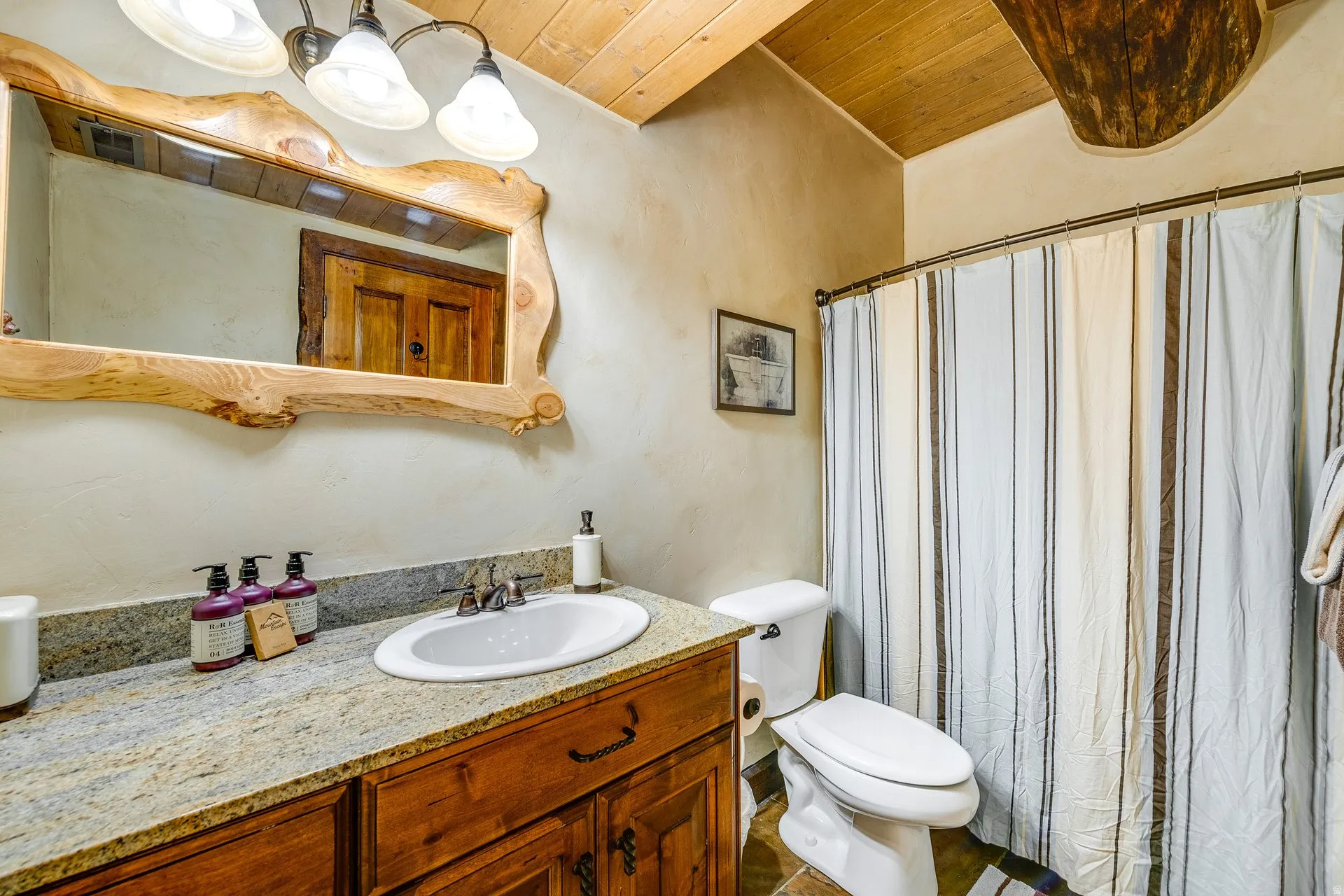 Bathroom featuring a wood-finish vanity with a light-toned, speckled countertop and an oval drop-in sink