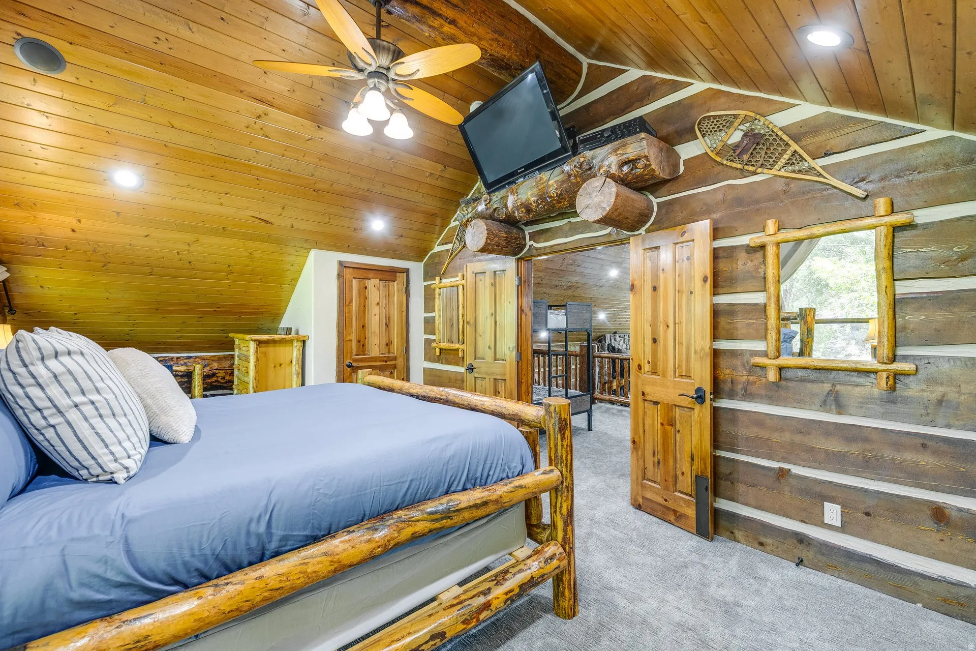 Rustic bedroom featuring log walls and a wood-paneled ceiling with recessed lighting