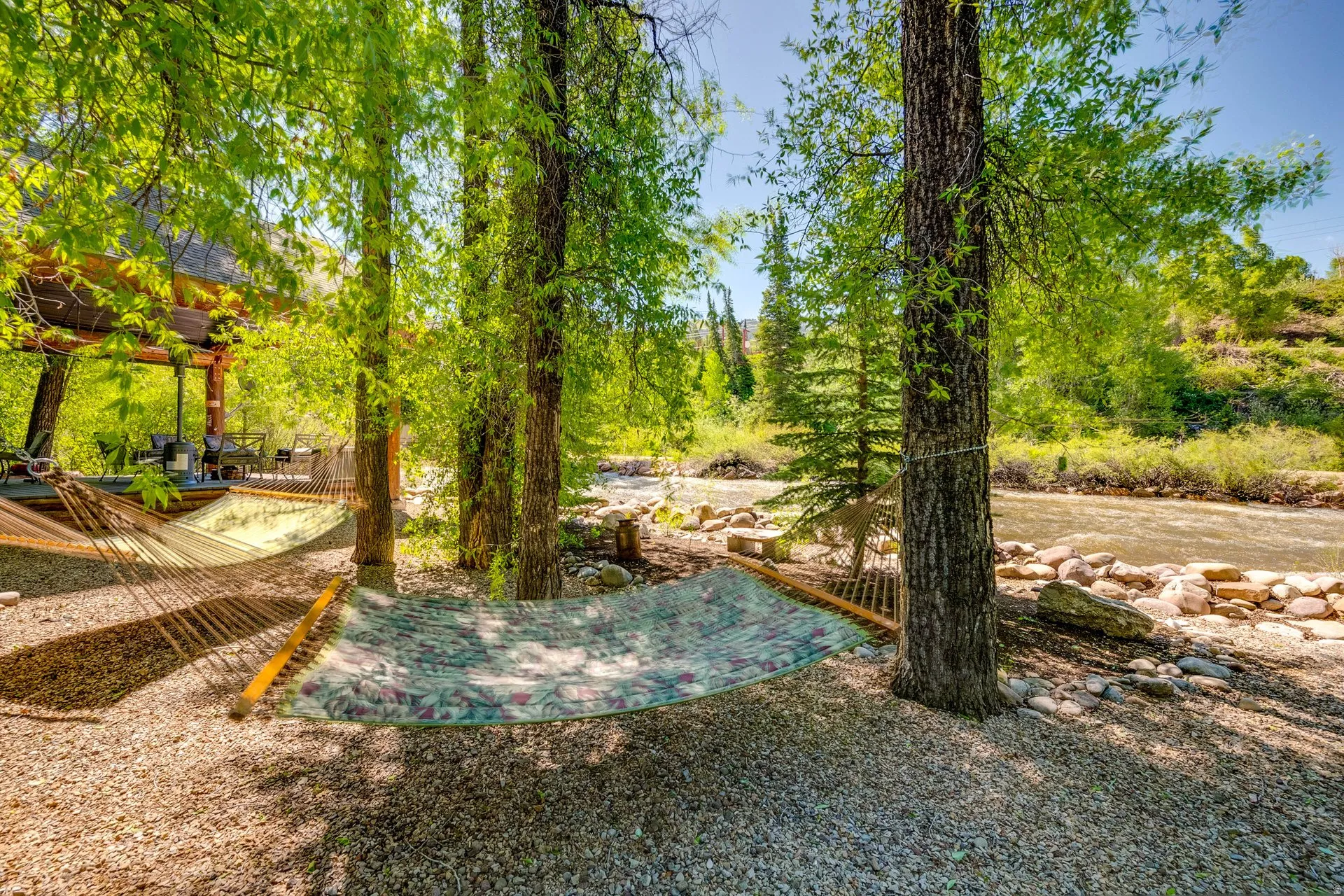 Riverside property featuring mature trees, a gravel ground covering, and a covered outdoor patio structure