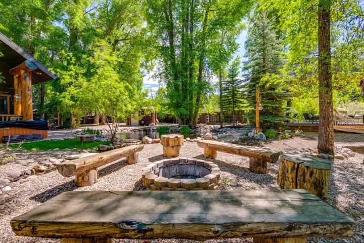 Outdoor entertainment area featuring a stone fire pit with surrounding log benches and stump seating