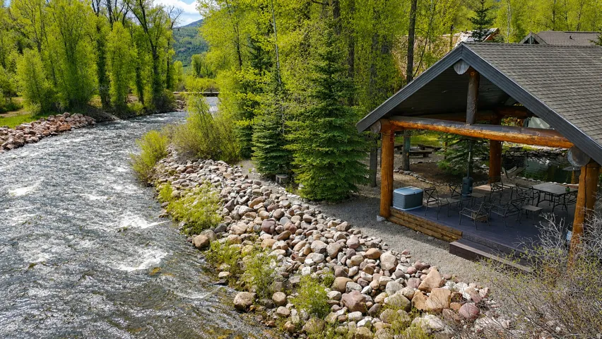 Riverfront outdoor pavilion featuring a gabled roof and exposed log beams