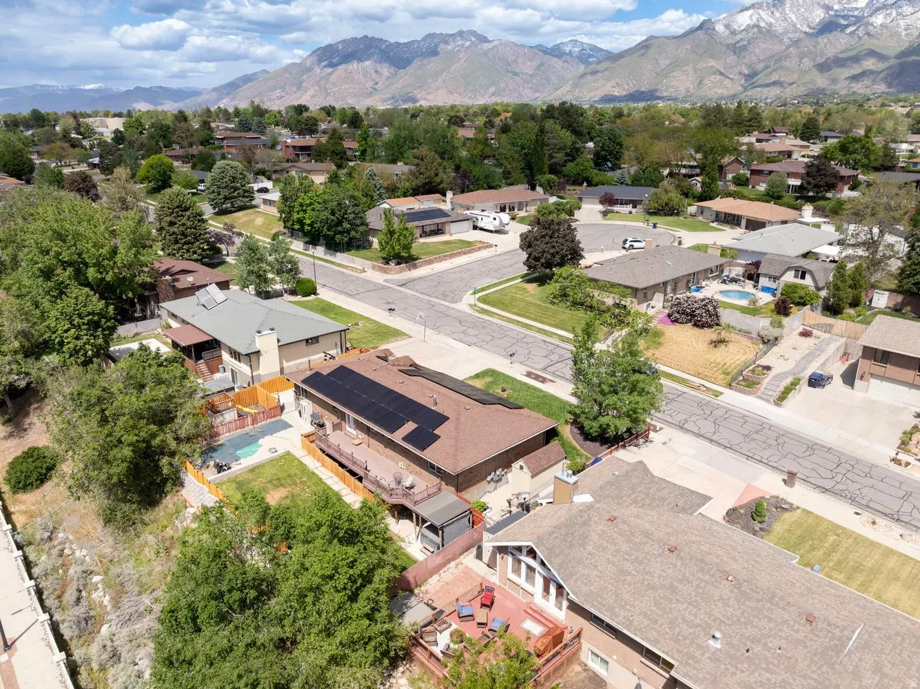 Residential property featuring an in-ground swimming pool, solar panel array, and multi-level decking