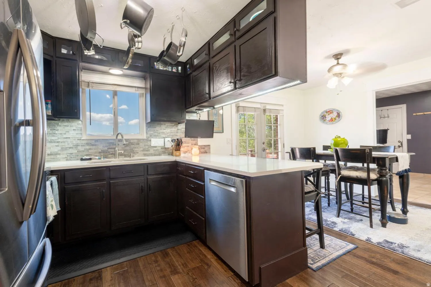Modern kitchen featuring dark wood cabinetry, stainless steel appliances, and a mosaic tile backsplash