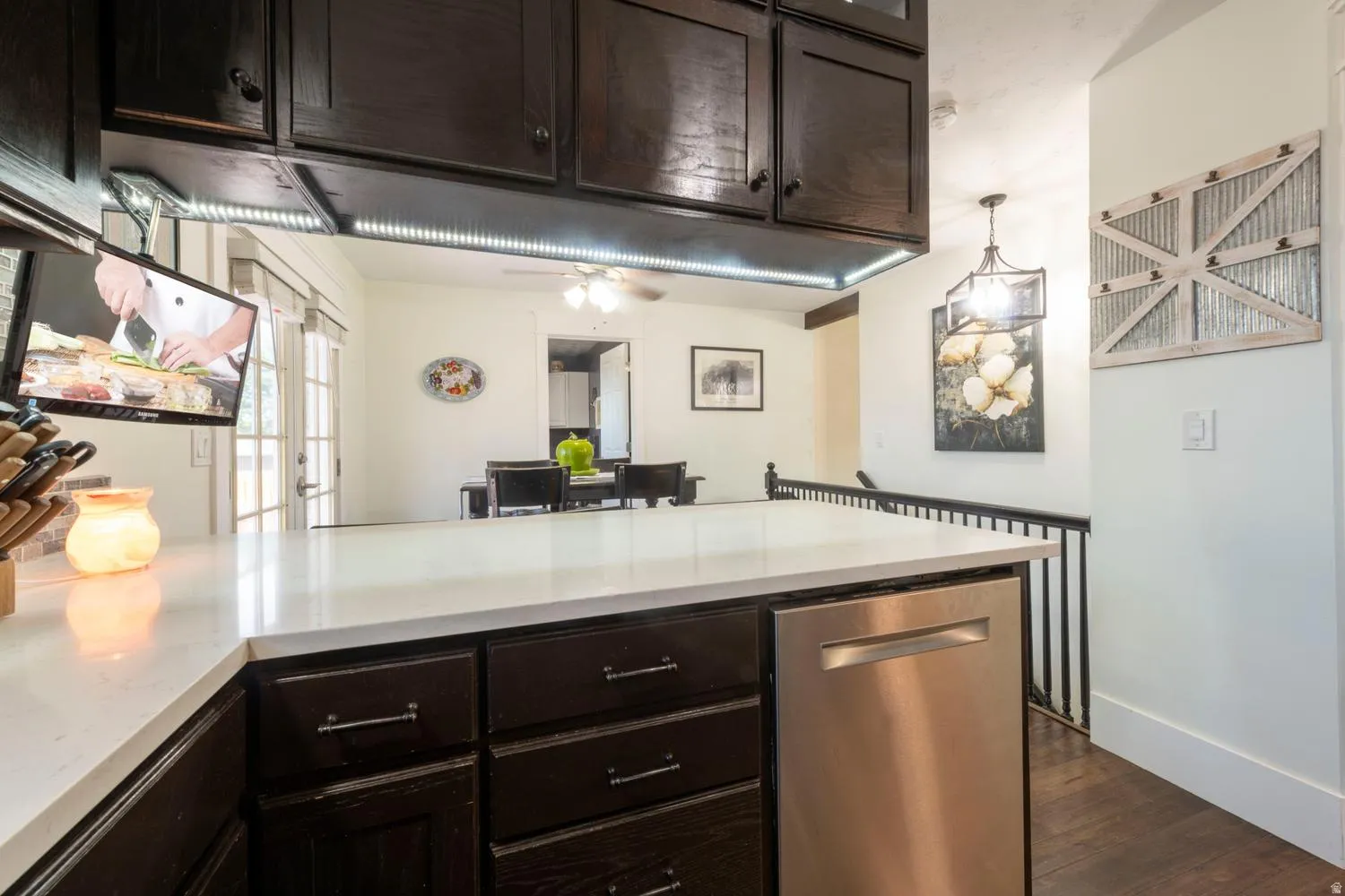 Kitchen island featuring a white countertop, dark wood-finish cabinetry, and a stainless steel dishwasher
