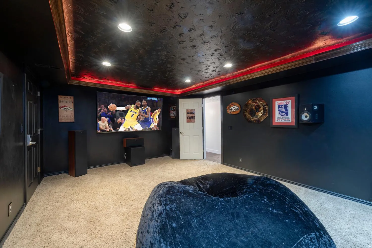 Dedicated media room featuring a large projection screen, dark wall finishes, and a textured black ceiling with recessed lighting