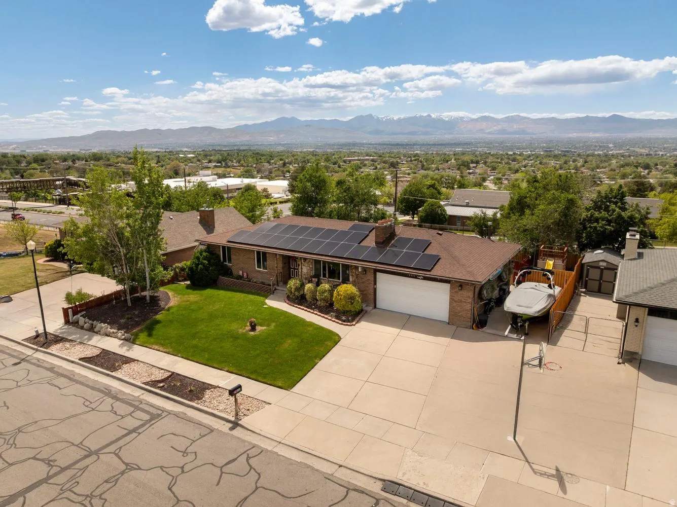 Brick exterior with solar panels, mature landscaping, and an attached garage