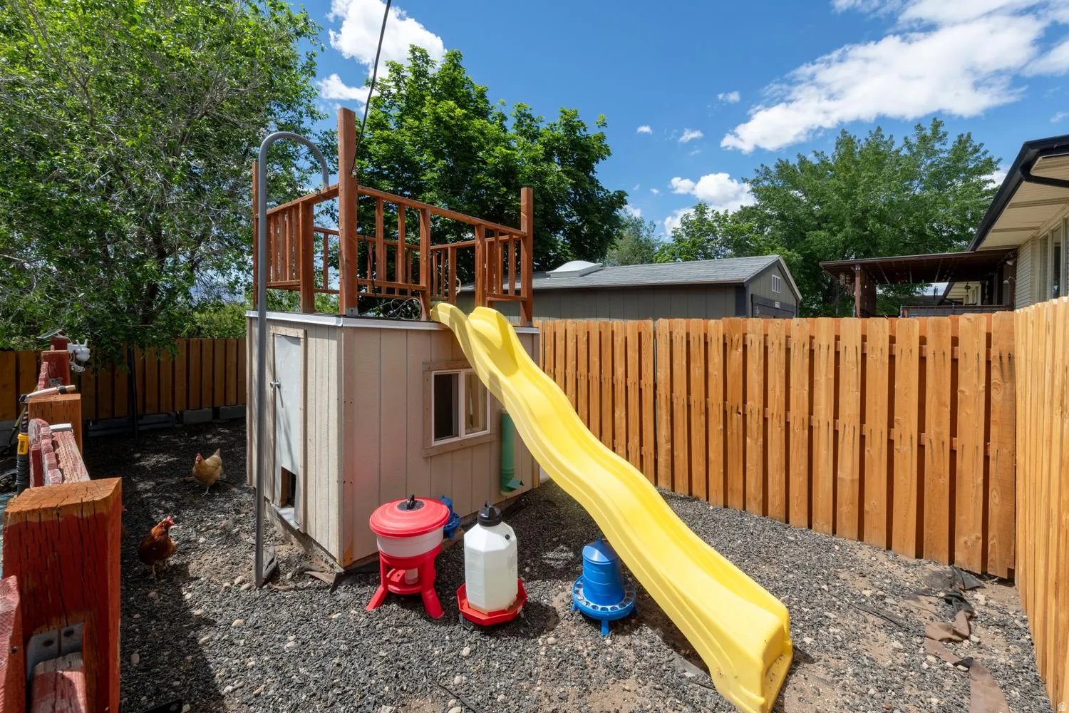 Outdoor structure with an upper deck, integrated slide, and a durable wood privacy fence