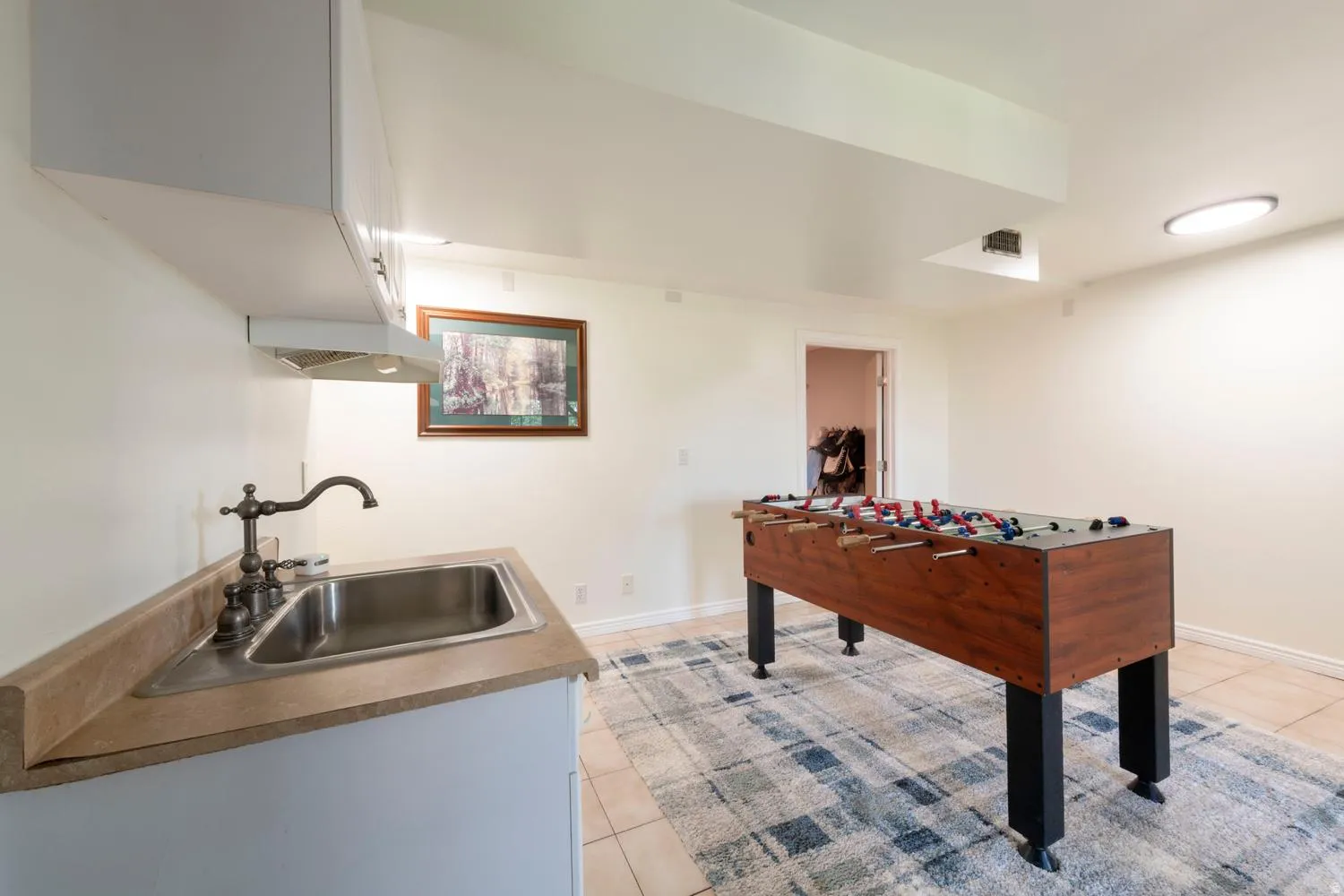 Utility area featuring an undermount stainless steel sink, a dark bronze faucet, and light-toned countertops