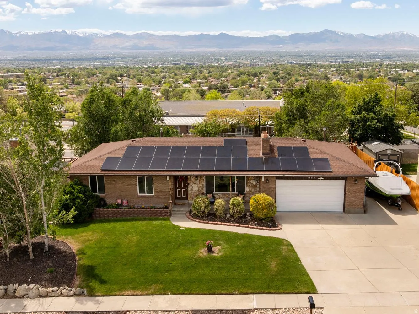 Brick and stone facade residence featuring a brown shingle roof with integrated solar panels