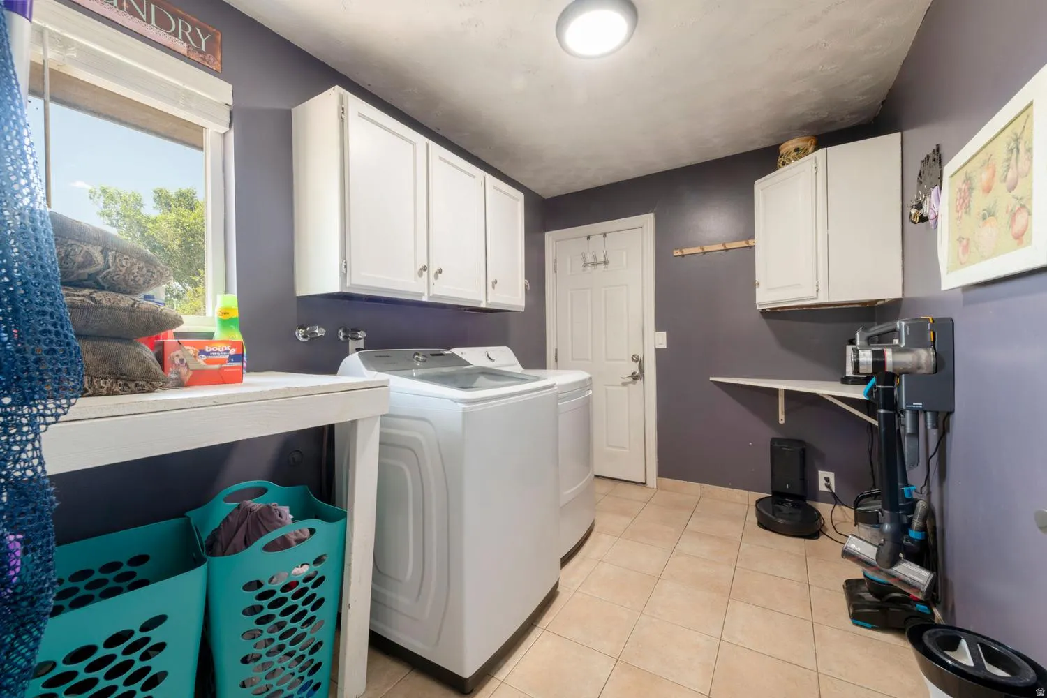Laundry area featuring tile flooring, white cabinetry, a built-in folding counter, and a window providing natural light