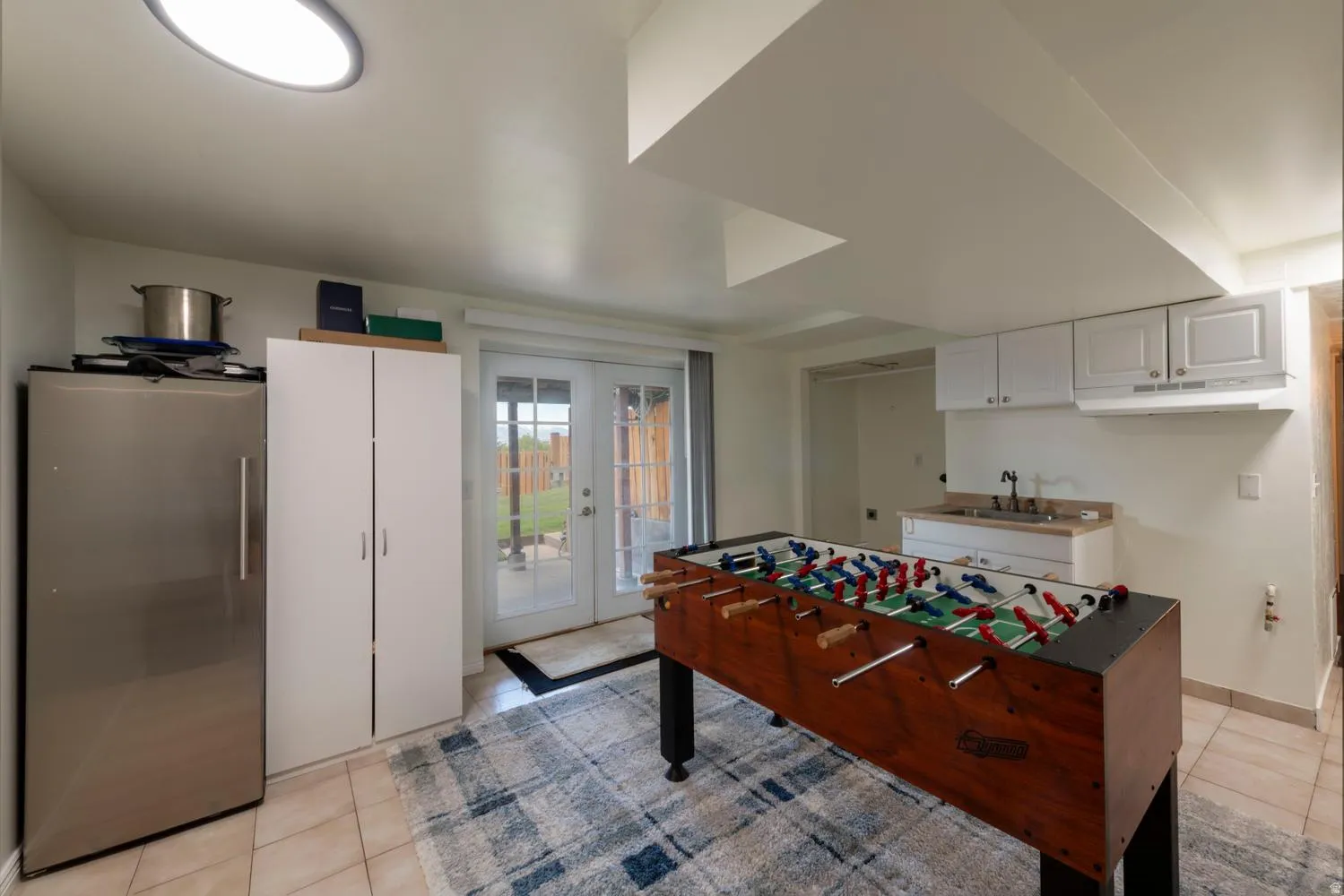 Room with tile flooring, recessed lighting, and a built-in wet bar with white cabinetry