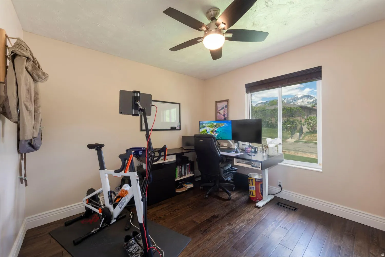 Room featuring wood-finish flooring, a contemporary ceiling fan with integrated lighting, and a window with mountain scenery