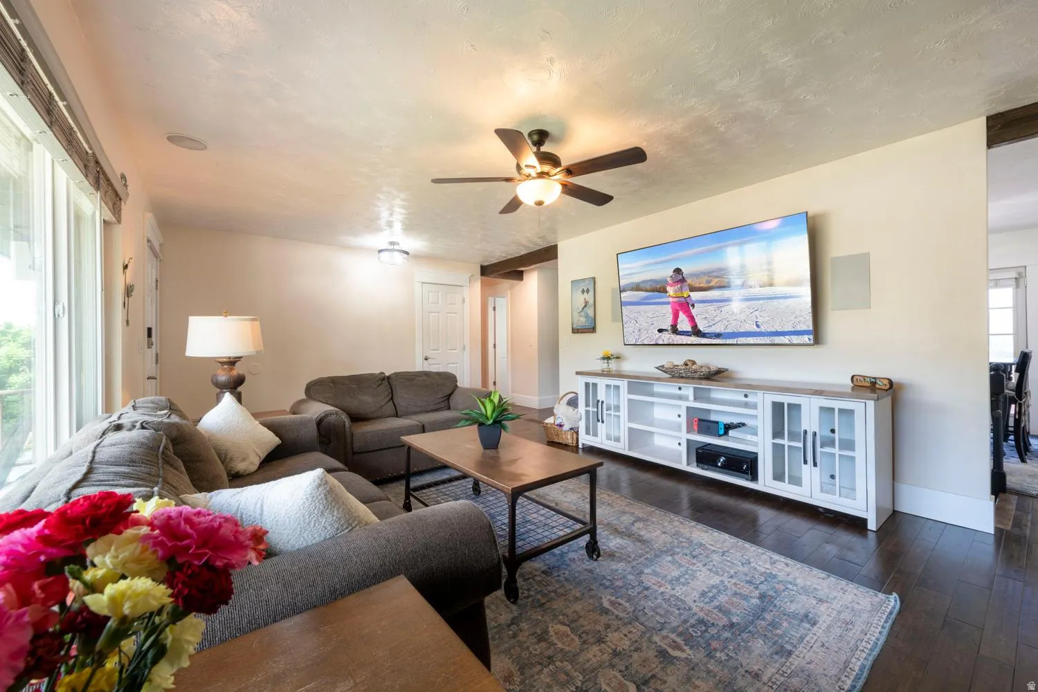 Spacious living area featuring dark wood-finish flooring and light-toned walls