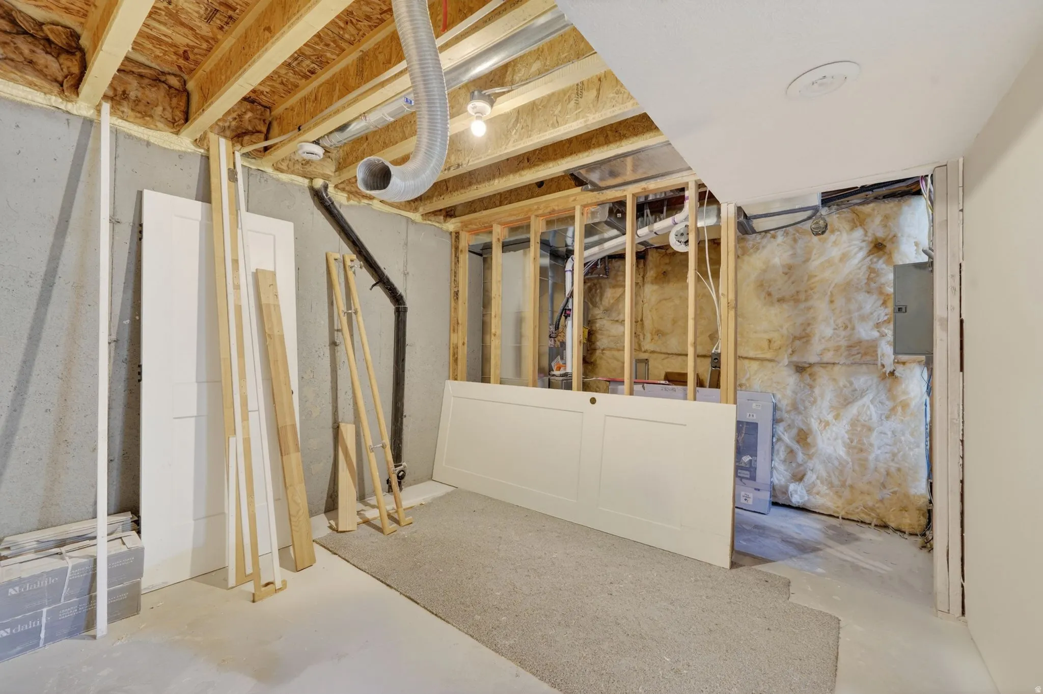 Unfinished basement space featuring exposed wood joists and concrete walls