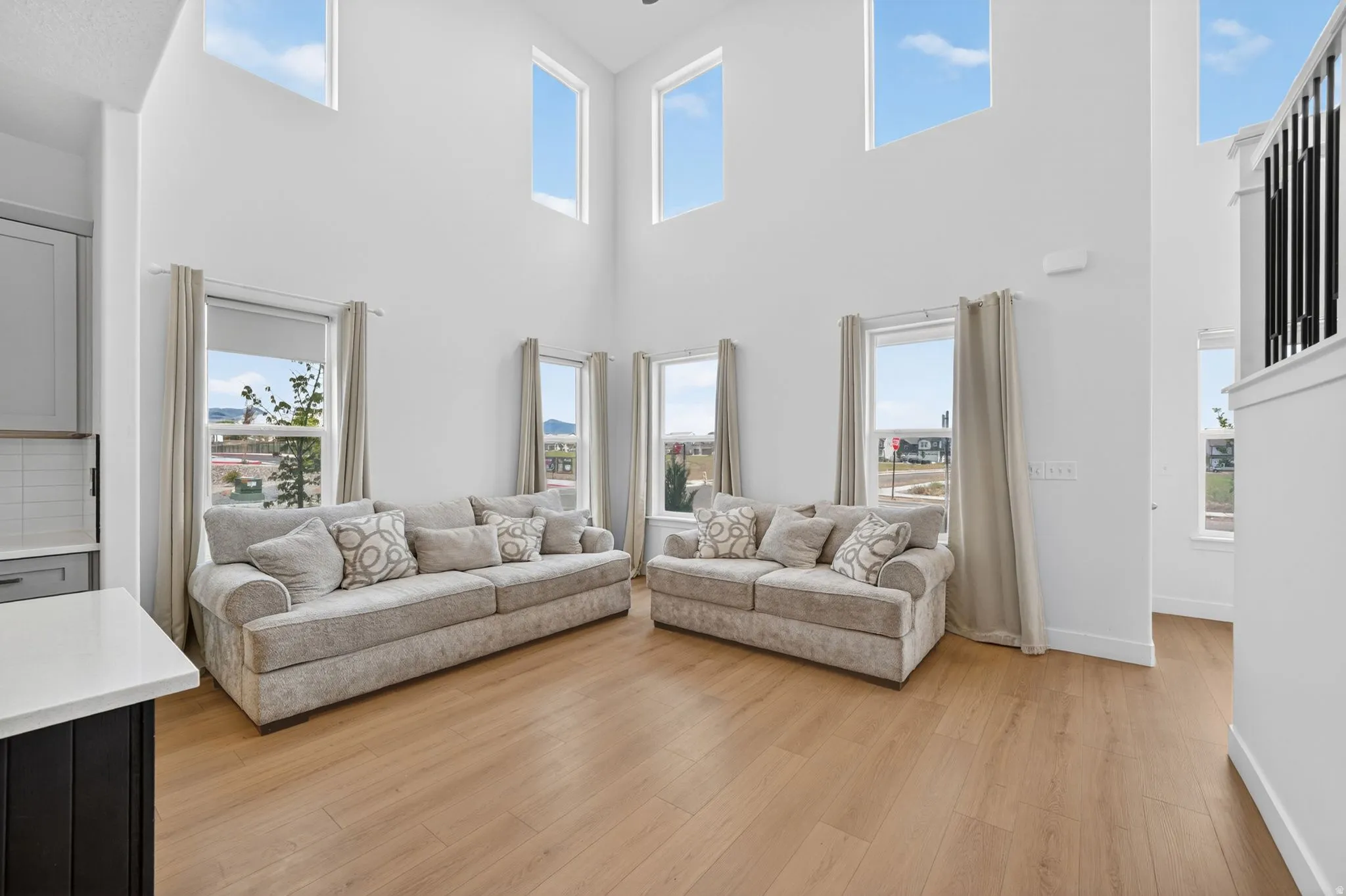 Double-height living area featuring high ceilings, light wood-finish flooring, and multiple large windows