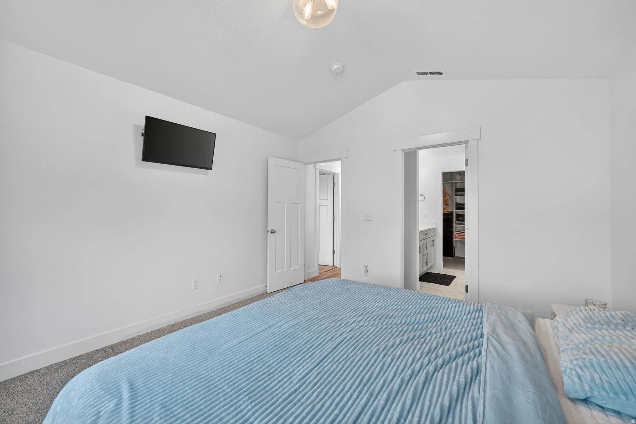 Vaulted ceiling bedroom with white walls, gray carpet, and white trim