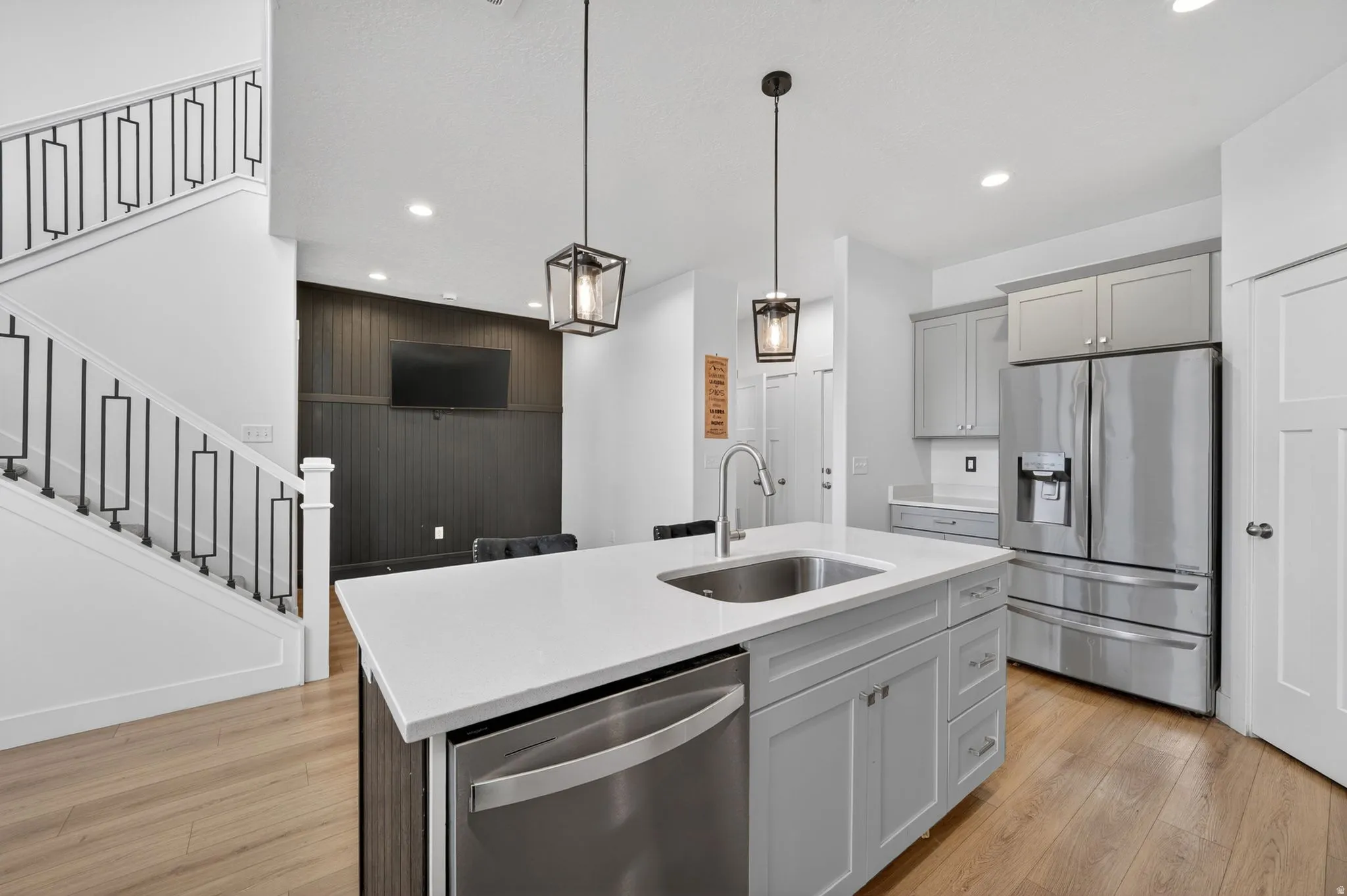Kitchen island with integrated sink, stainless steel dishwasher, and two pendant lights