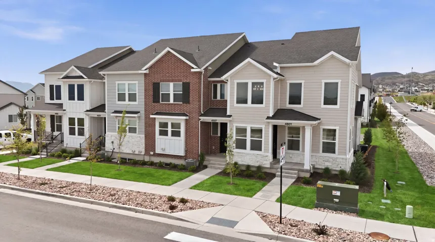 Contemporary townhome facade featuring a mix of brick, horizontal siding, and stone accents