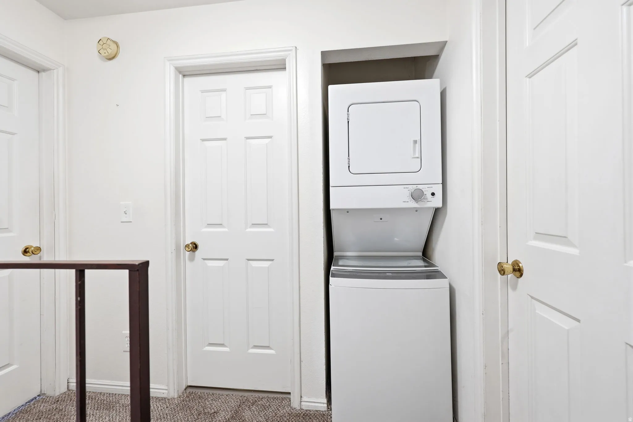 Dedicated laundry alcove featuring a stacked white washer and dryer unit