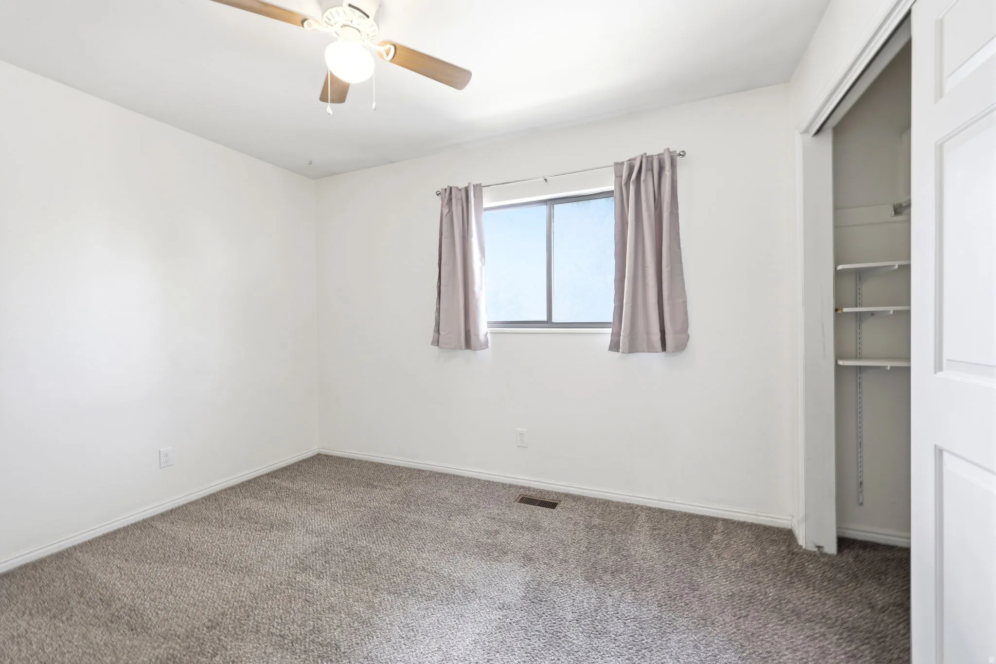 Neutral color palette bedroom featuring textured gray carpet and white painted walls